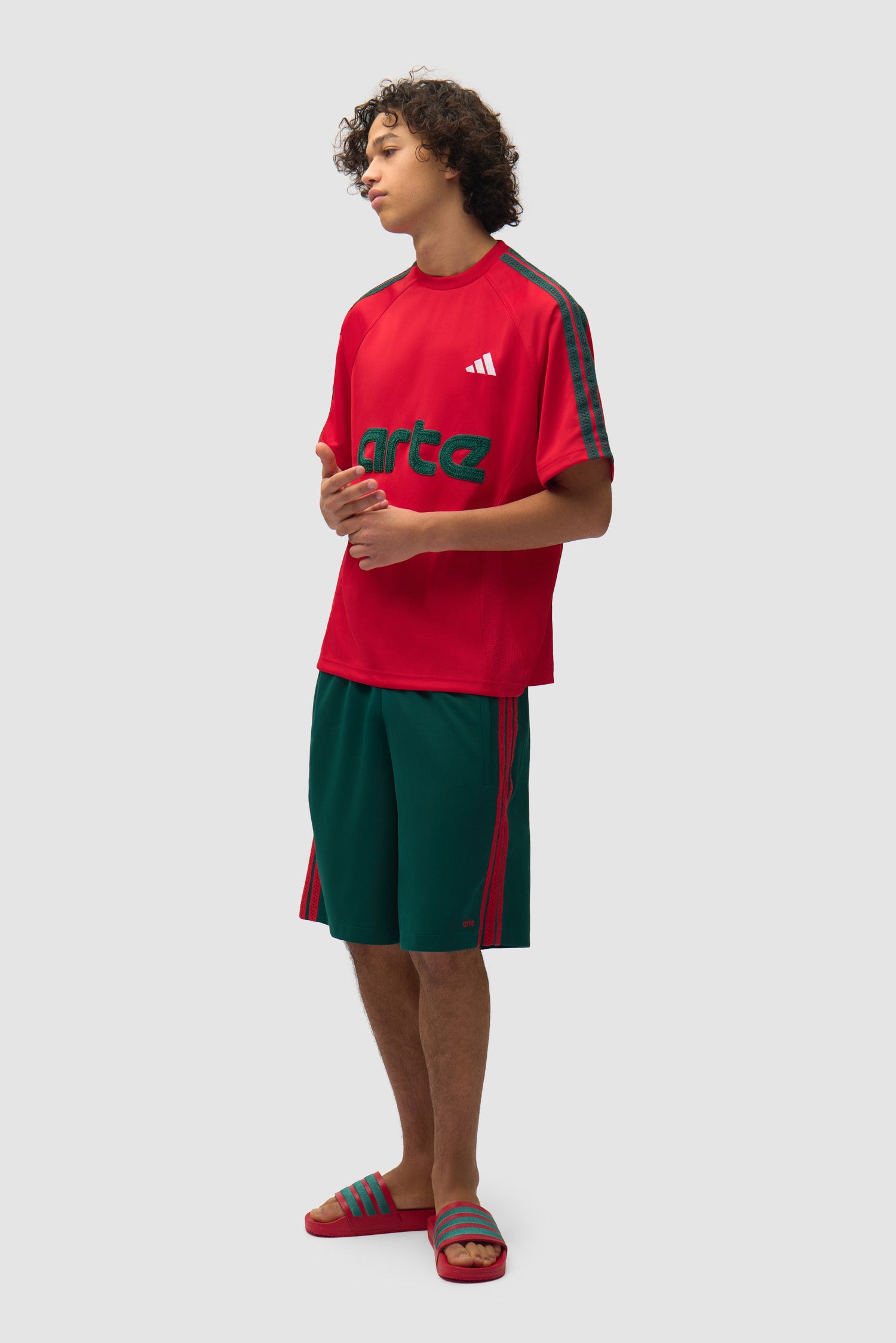 Short Arte pour adidas vert universitaire porté par un mannequin, vue de profil en pied