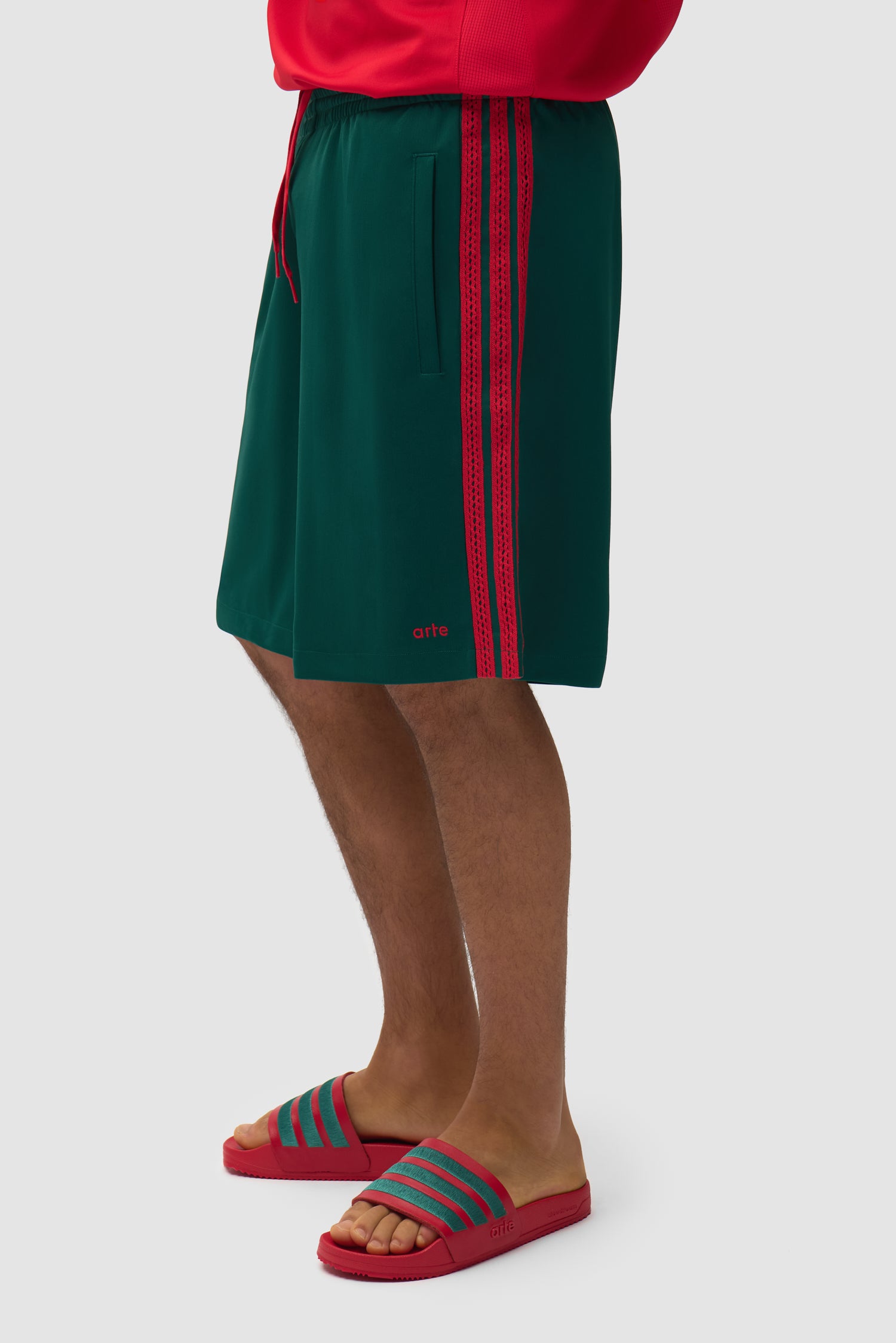 Arte pour adidas Short vert universitaire porté par un mannequin, vue de profil à mi-corps