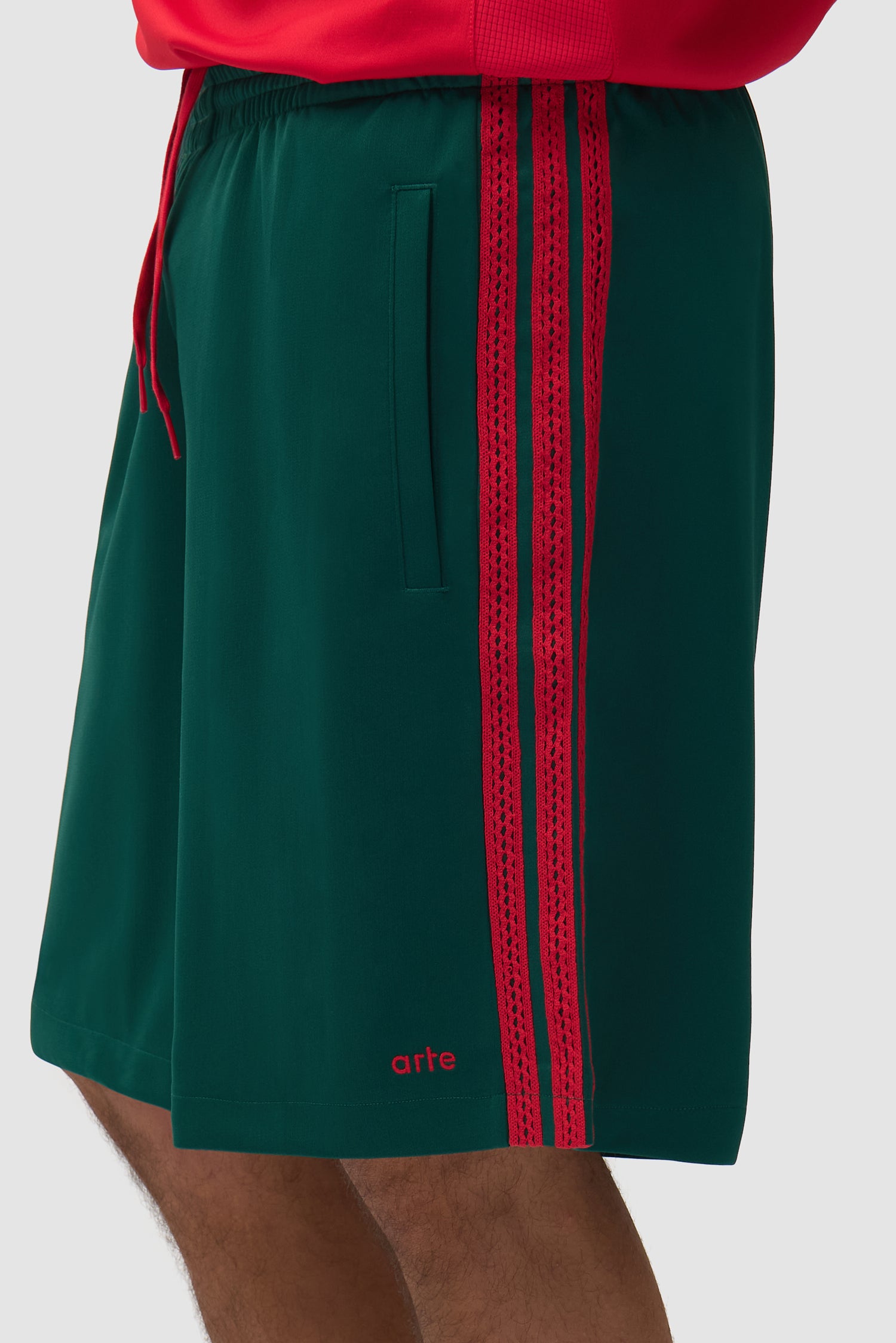 Vue détaillée du short Arte pour adidas en vert universitaire, avec bandes latérales
