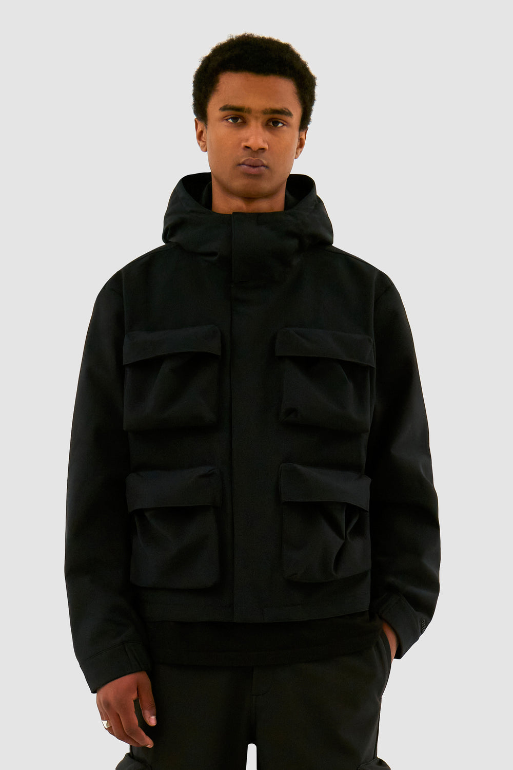 Veste à capuche en nylon avec poches 3D, couleur noire, portée par un mannequin, vue de face, demi-corps