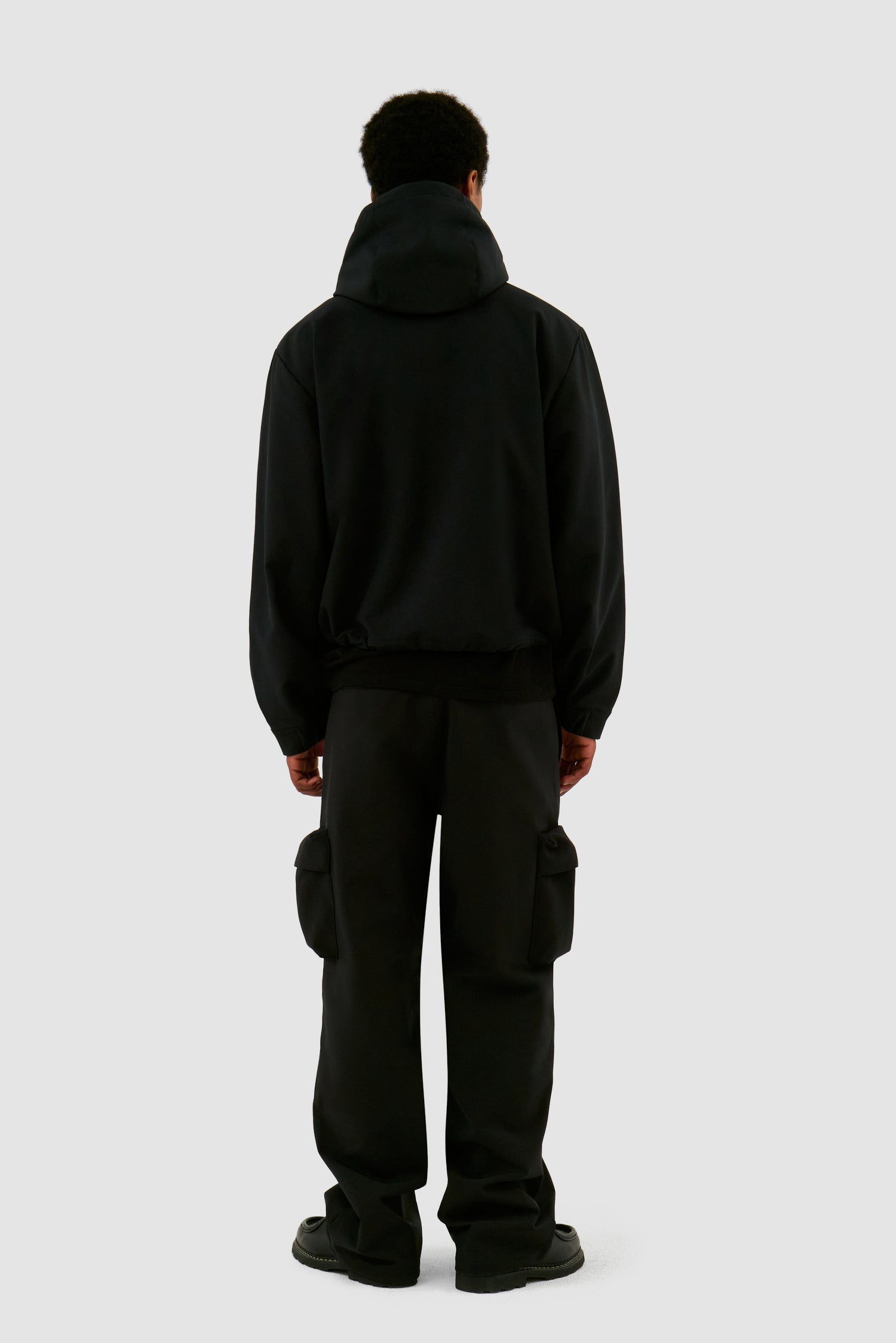 3D Pockets Hooded Nylon Jacket in Black worn by a model, full-body side view