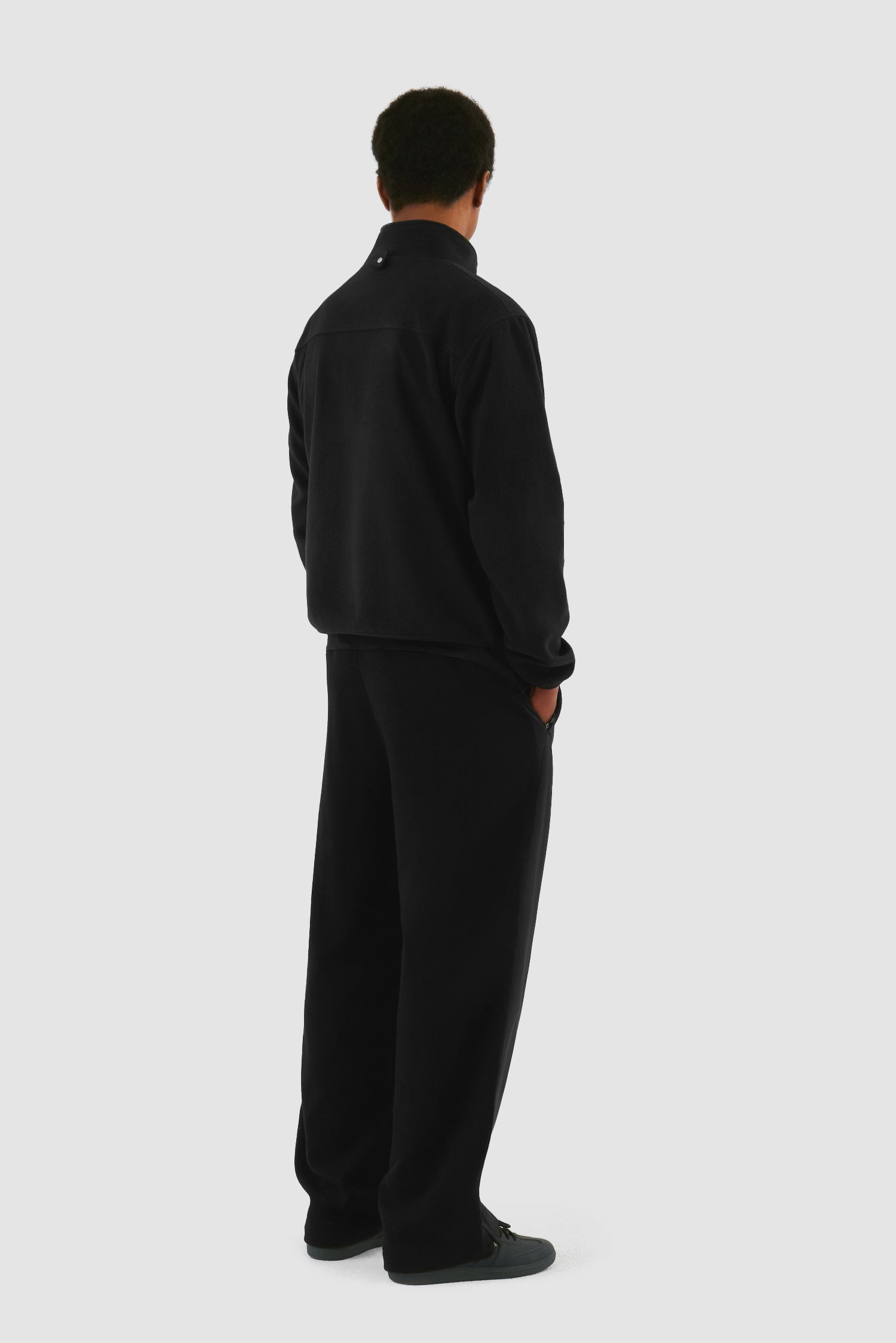 Wool Technical Jacket in Black worn by a model, full-body back view showing the inside layer