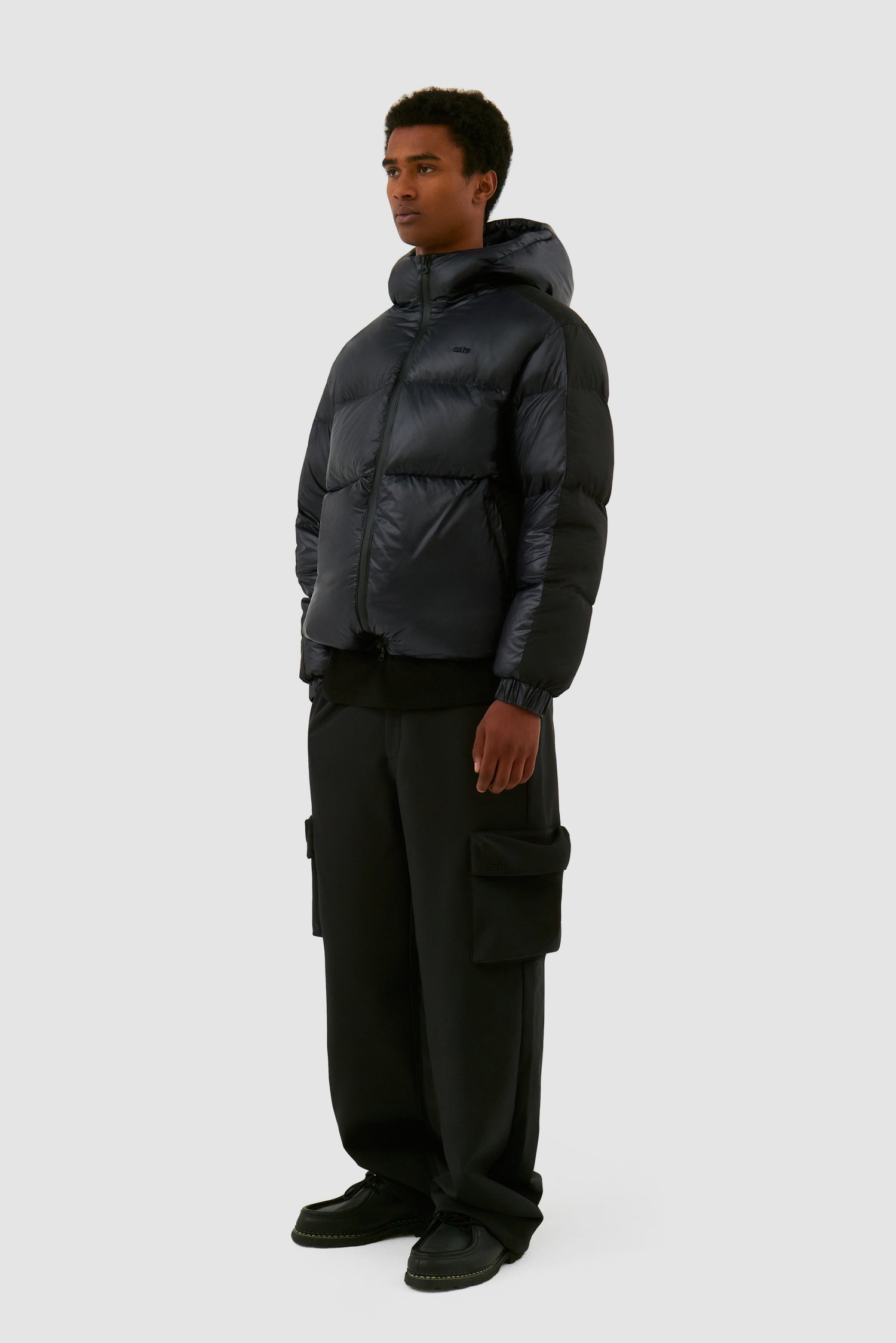 Shiny Puffer Jacket in Black worn by a model, full-body side view