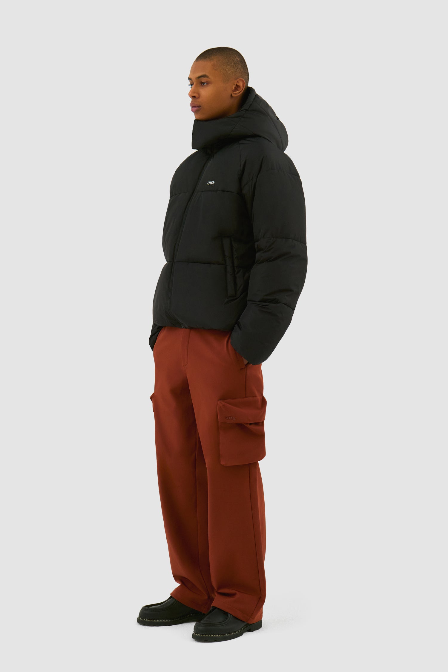 Puffer Jacket in Black worn by a model, full-body side view