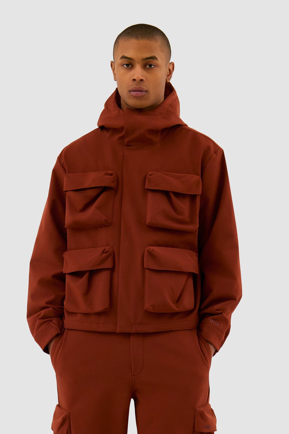 Veste à capuche en nylon orange avec poches 3D portée par un mannequin, vue de face en demi-corps