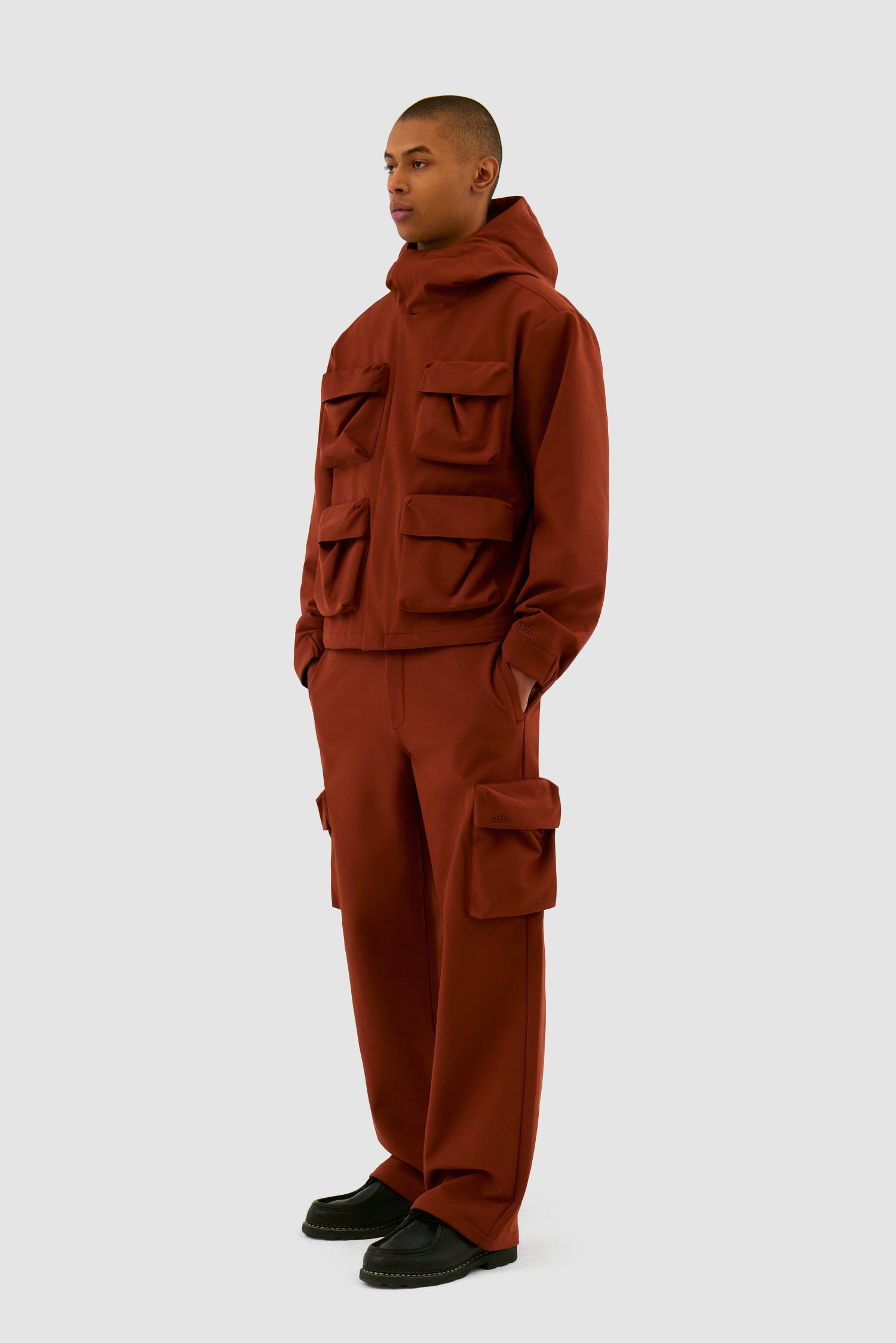3D Pockets Hooded Nylon Jacket in Orange worn by a model, full-body side view