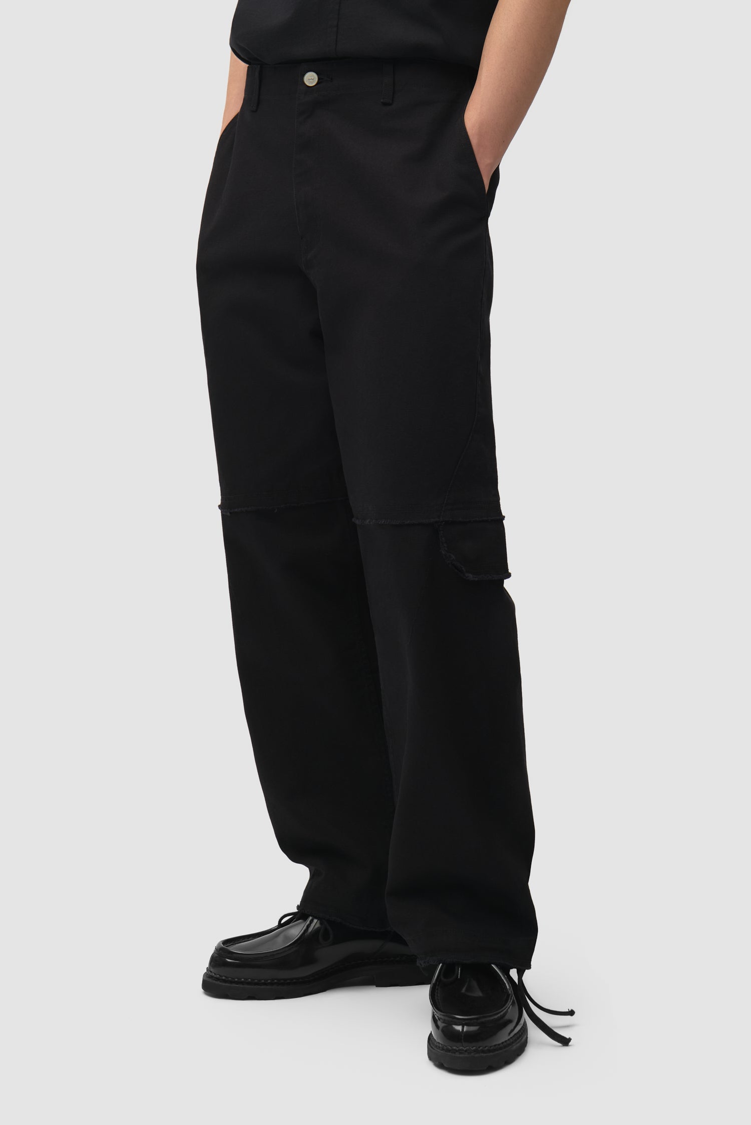 Pantalon cargo déstructuré noir porté par un mannequin, vue de face (mi-corps)