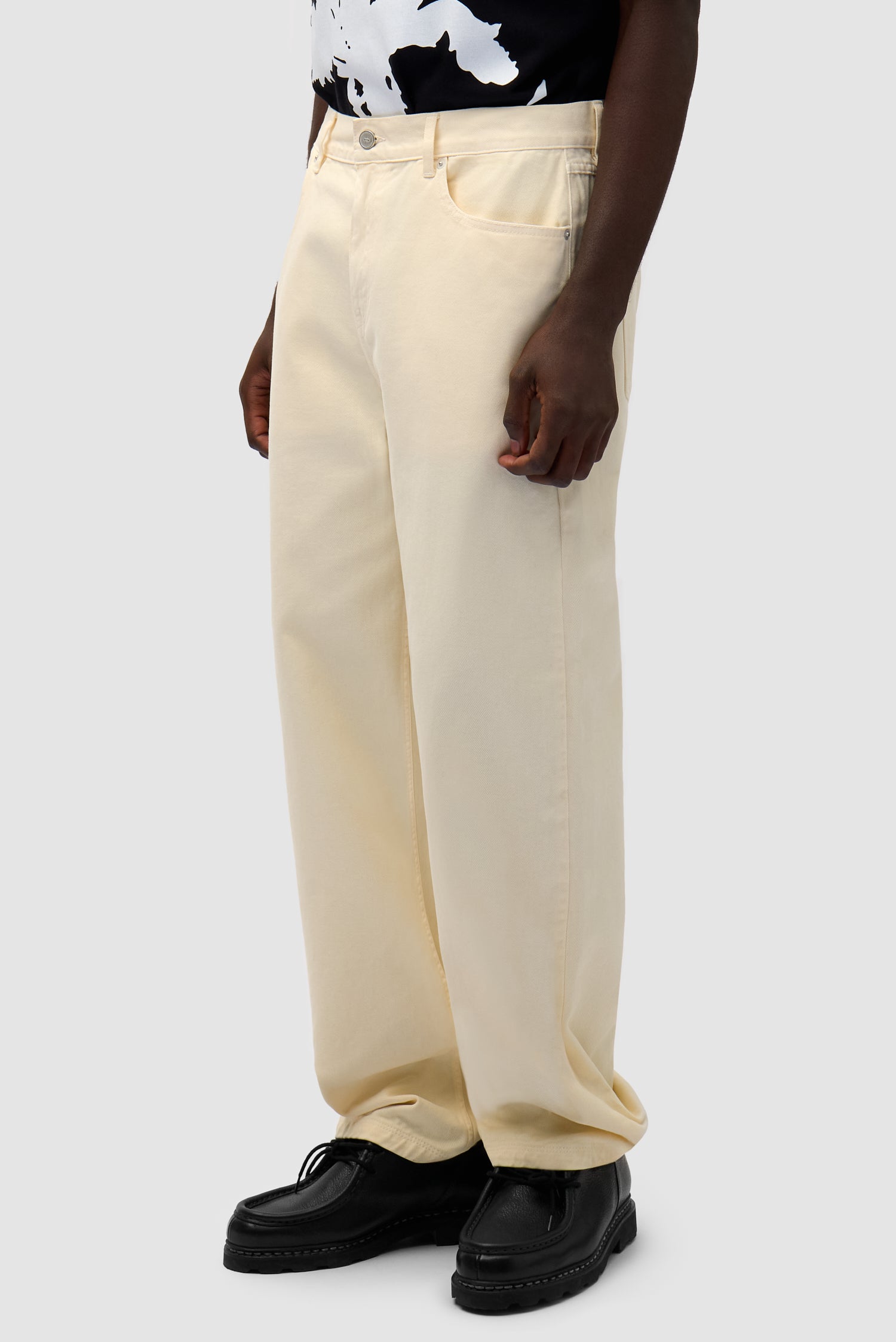 Back Bird Pants in Cream worn by a model, half-body side view