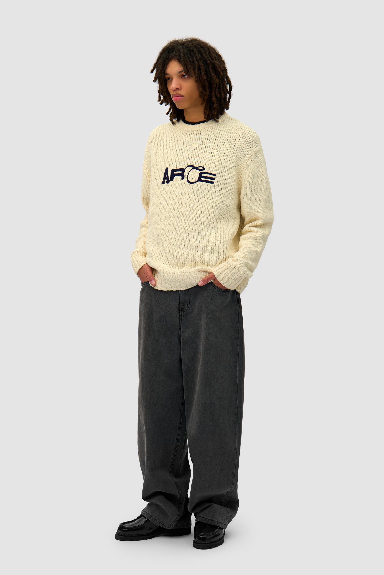 Logo Knit Sweater in Cream worn by a model, full-body side view
