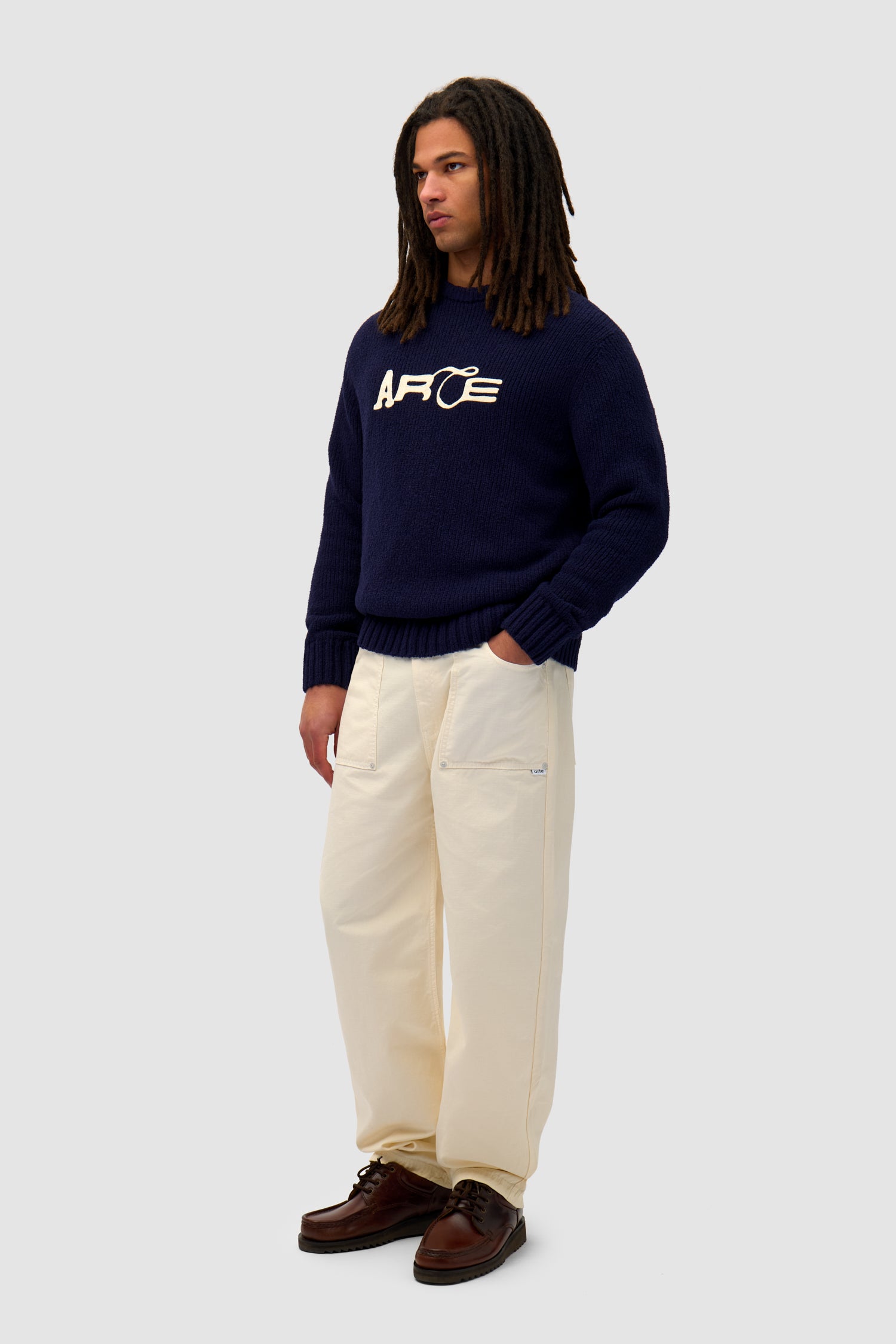 Logo Knit Sweater in Navy worn by a model, full-body side view