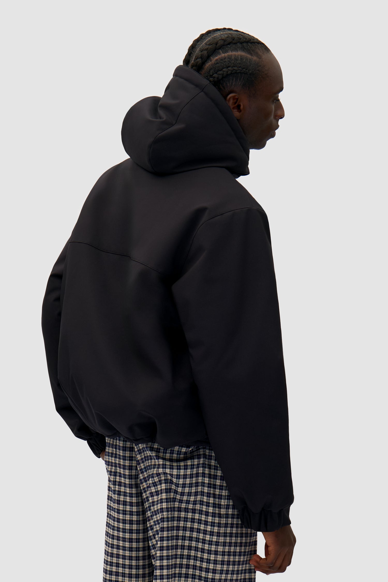 Technical Anorak in Black worn by a model, half-body back view
