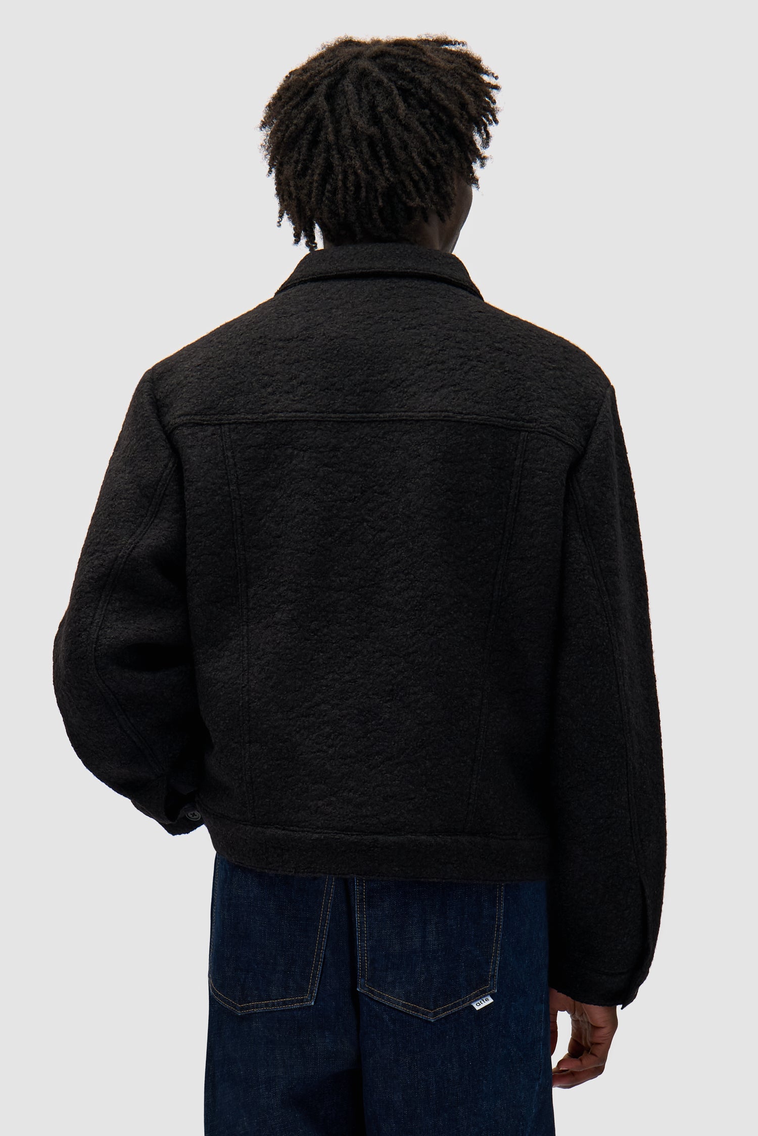 Wool Jacket in Black worn by a model, half-body back view