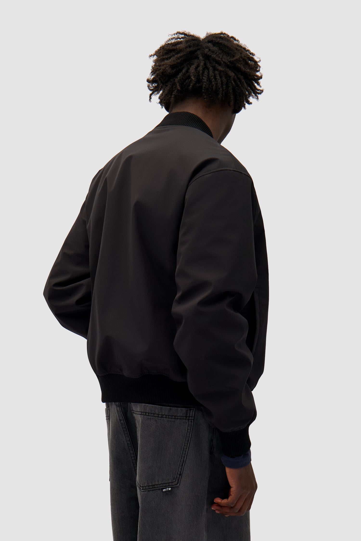 Logo Bird Bomber Jacket in Black worn by a model, half-body back view
