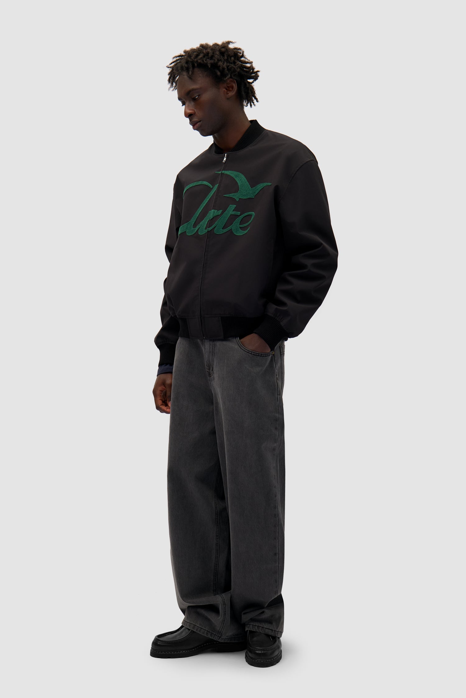 Logo Bird Bomber Jacket in Black worn by a model, full-body side view