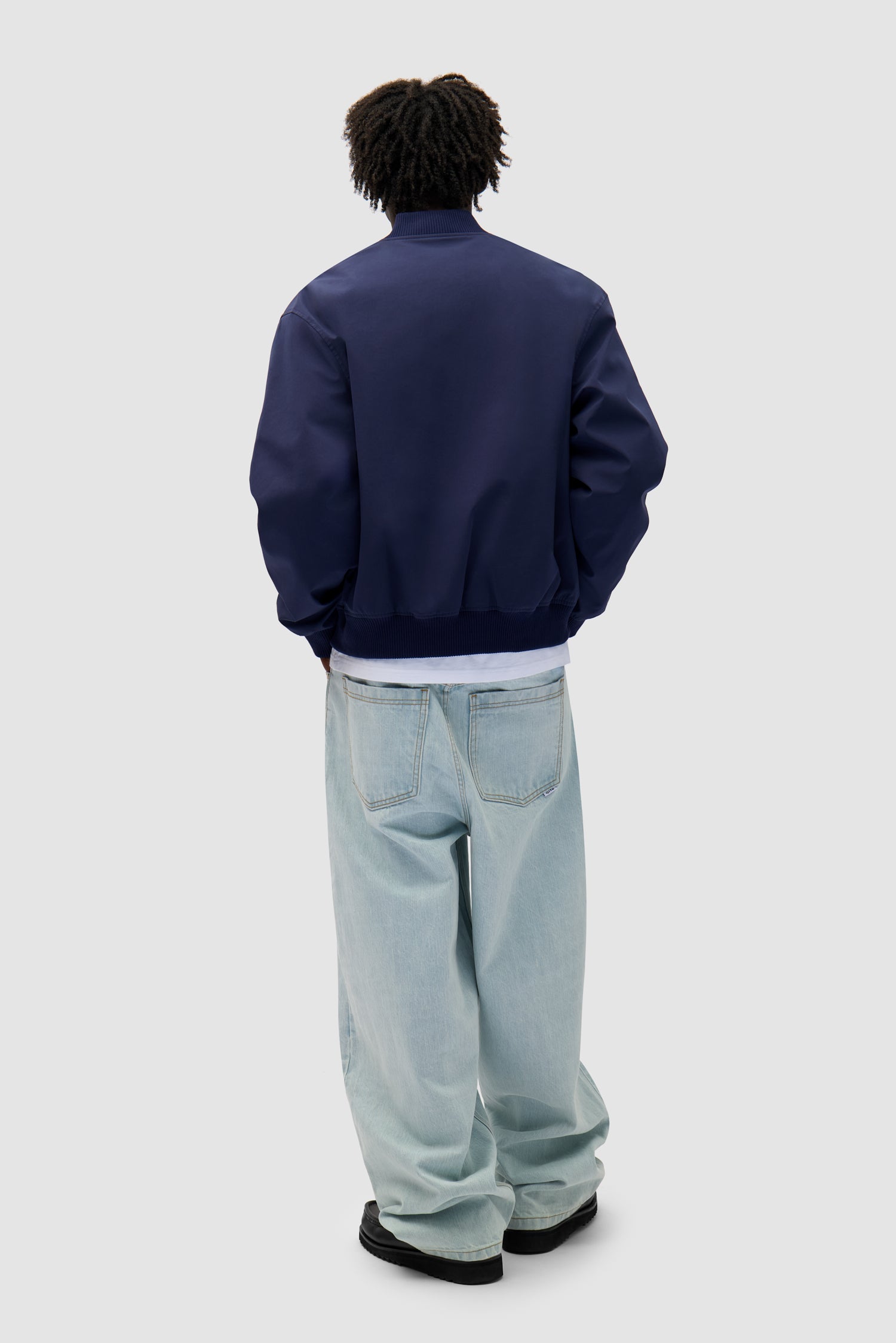 Logo Bird Bomber Jacket in Navy worn by a model, full-body back view