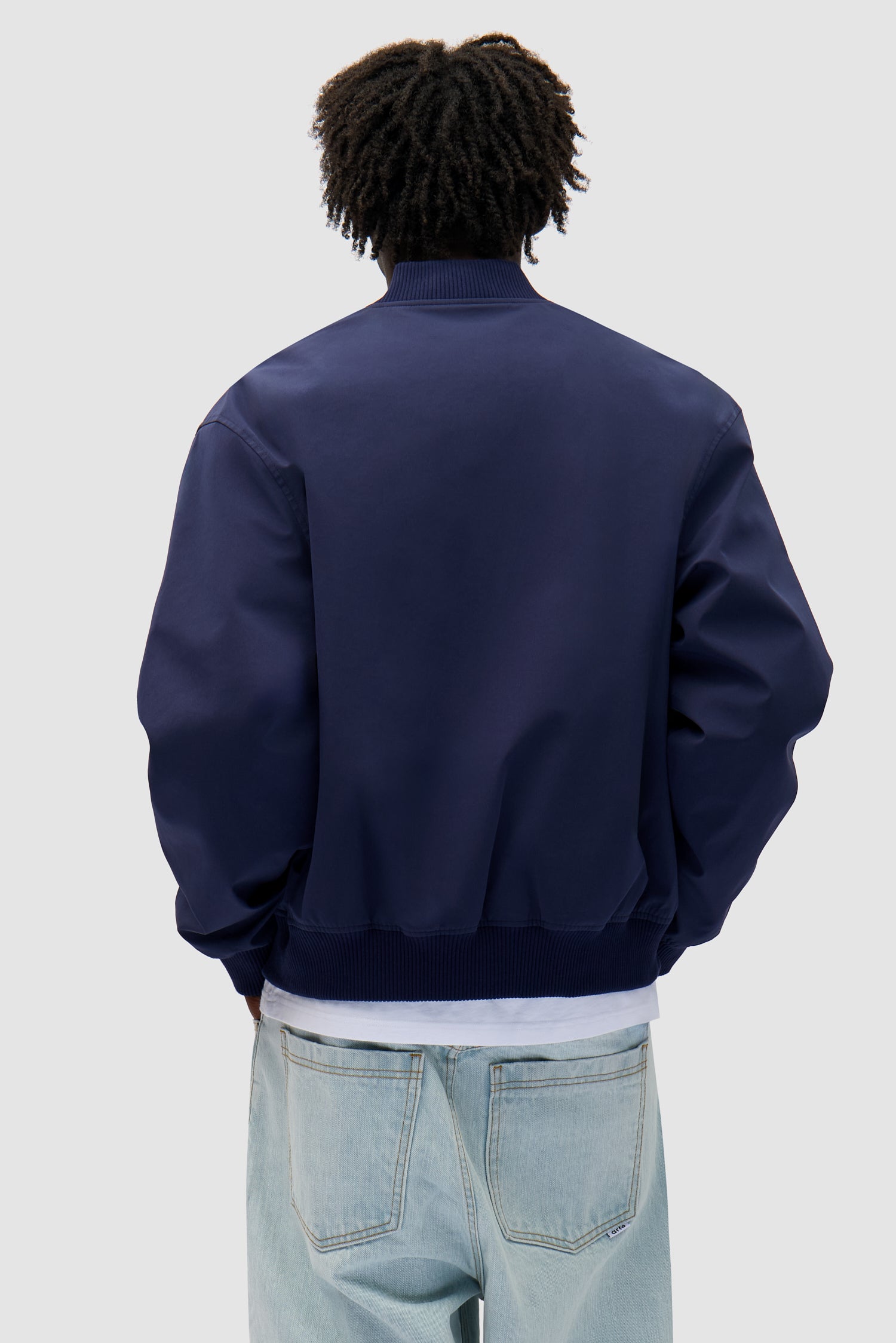 Logo Bird Bomber Jacket in Navy worn by a model, half-body back view