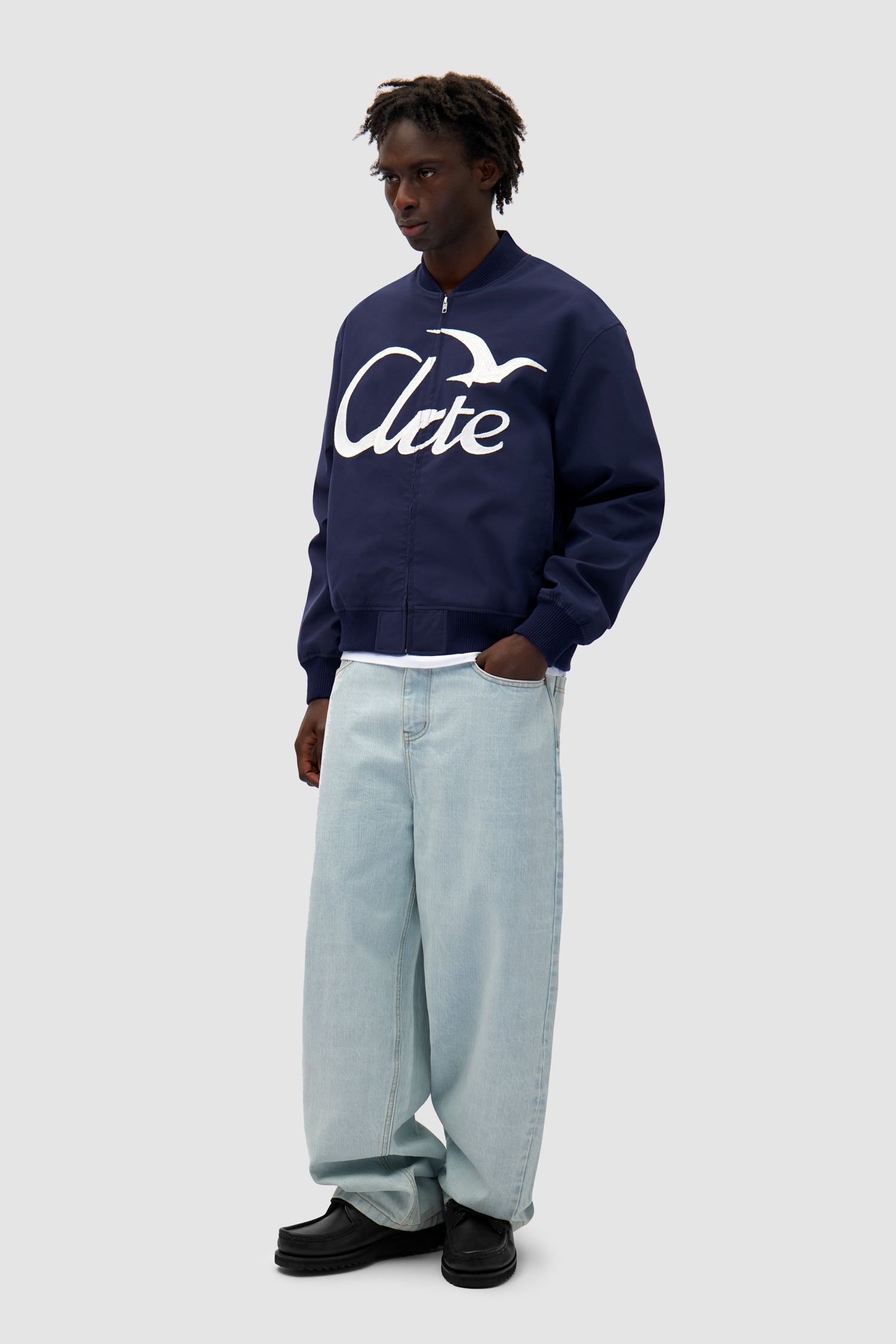 Logo Bird Bomber Jacket in Navy worn by a model, full-body side view