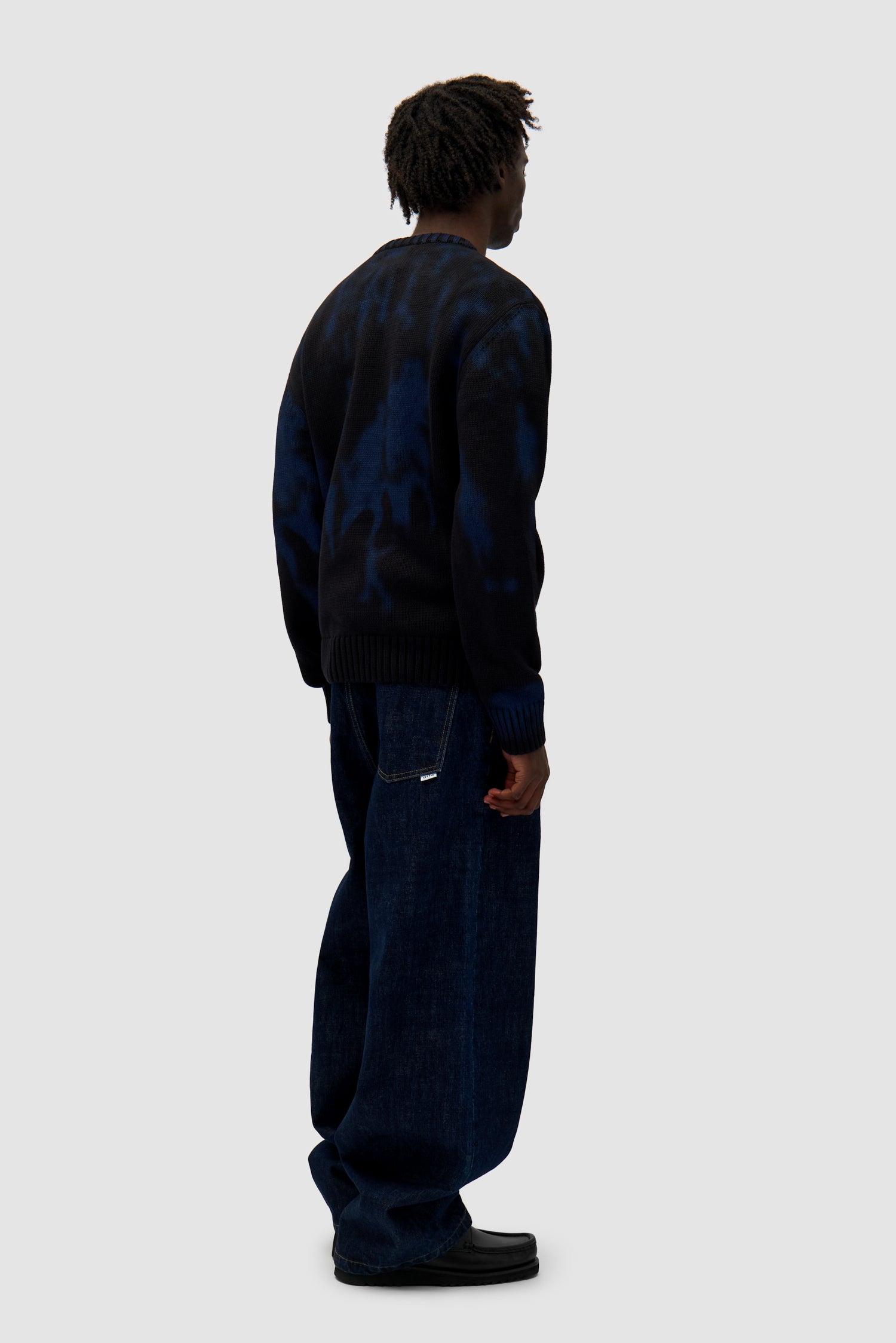 People Knit Sweater in Black/Navy worn by a model, full-body back view