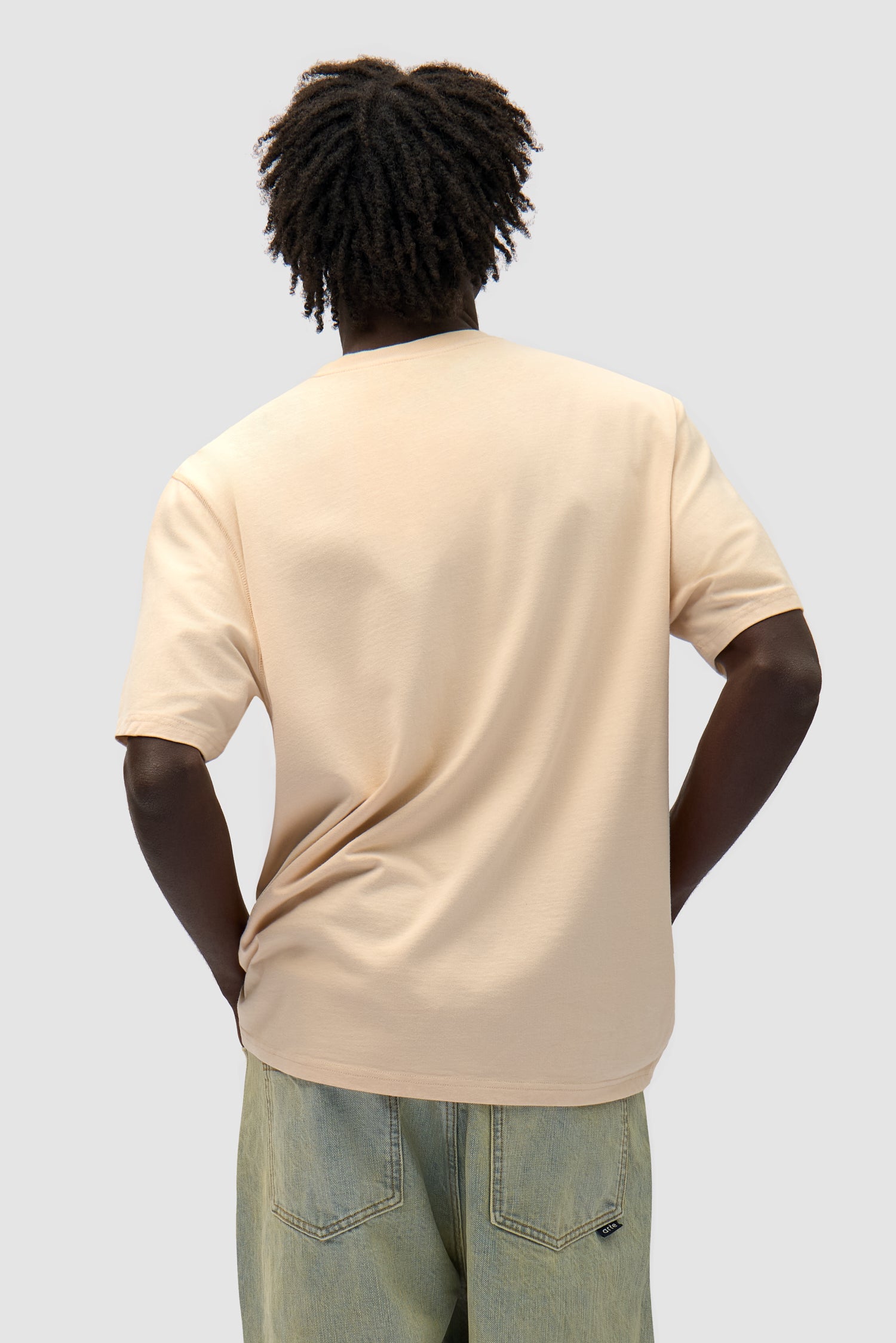 Multi Logo T-shirt in Cream worn by a model, half-body back view