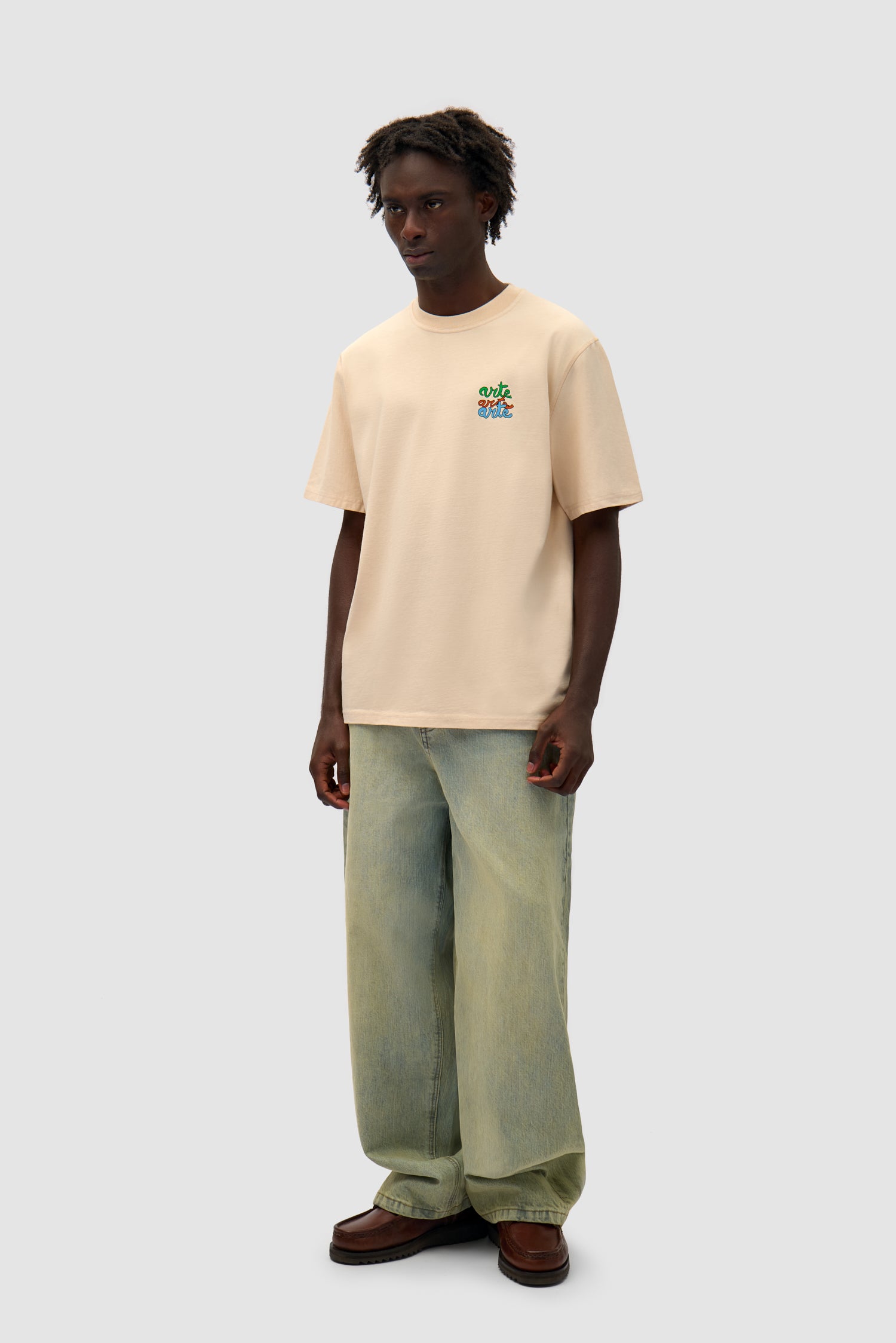 Multi Logo T-shirt in Cream worn by a model, full-body side view