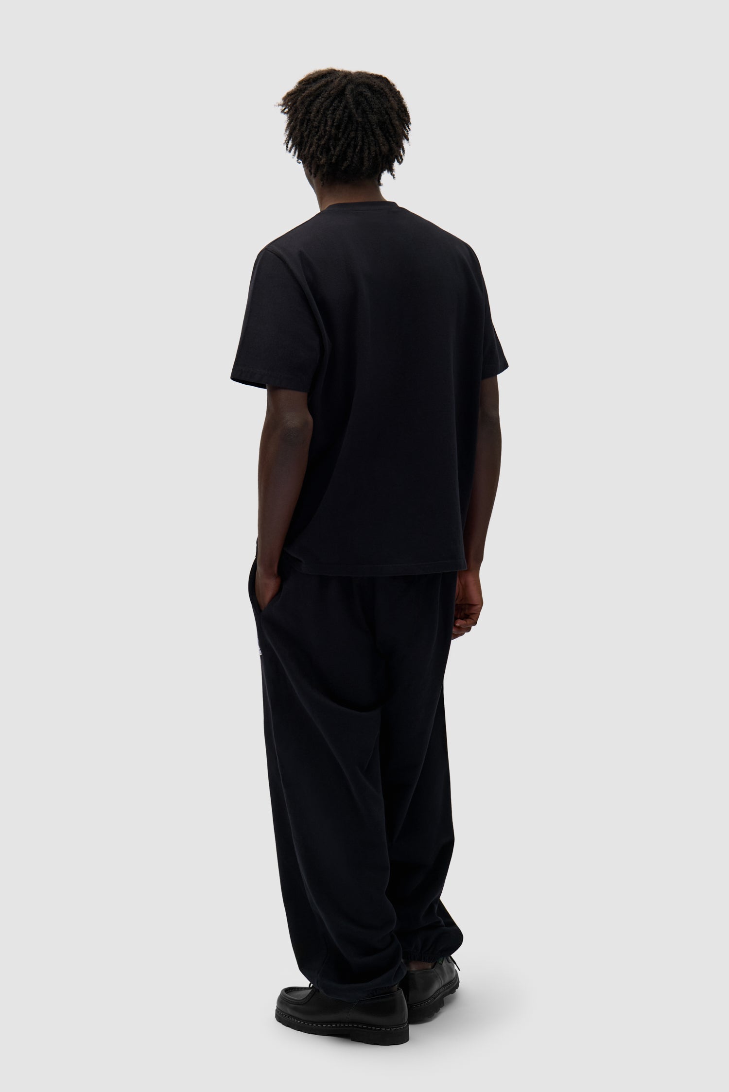 Heart Logo T-shirt in Black worn by a model, full-body back view