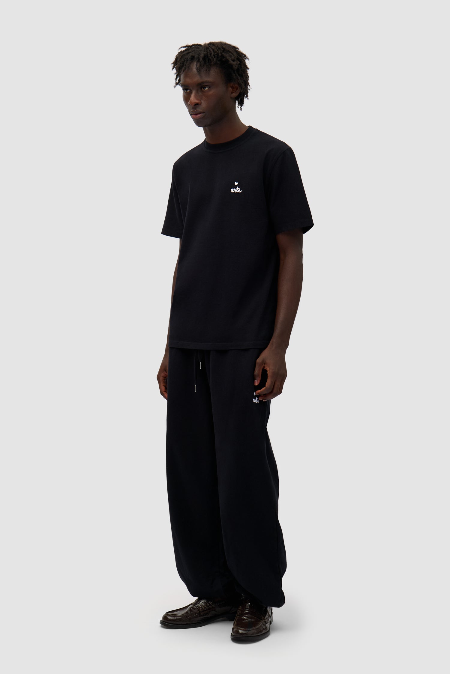 Heart Logo T-shirt in Black worn by a model, full-body side view