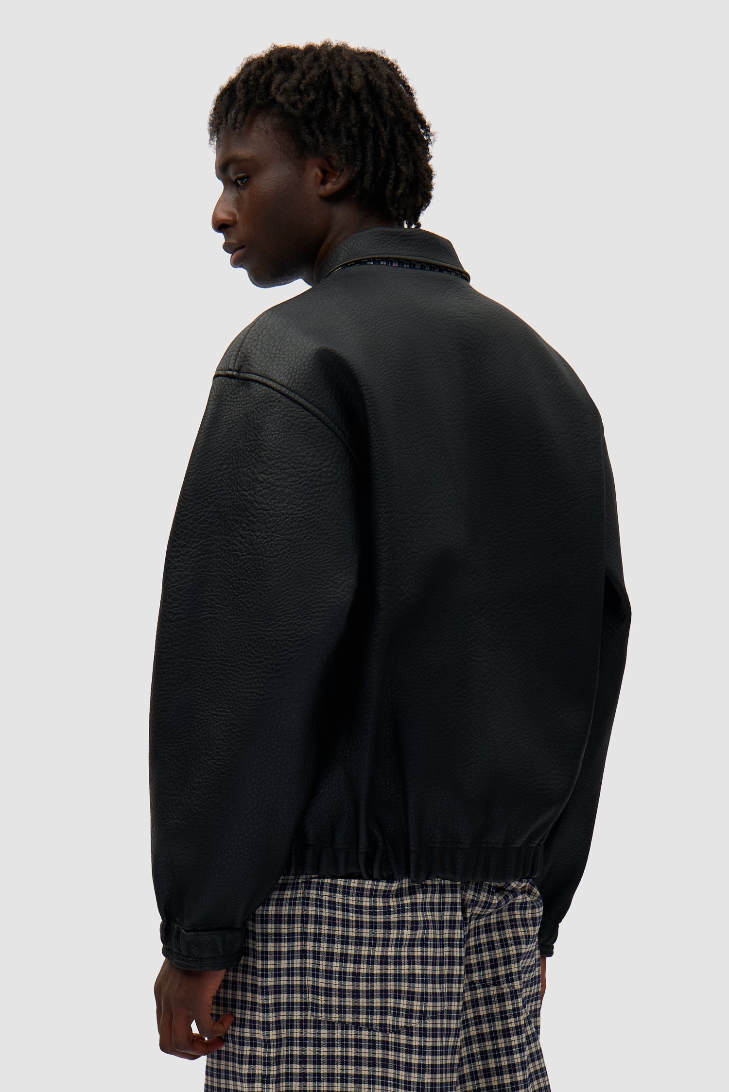 Reversible Plaid Leather Jacket in Black/Plaid worn by a model, half-body back view