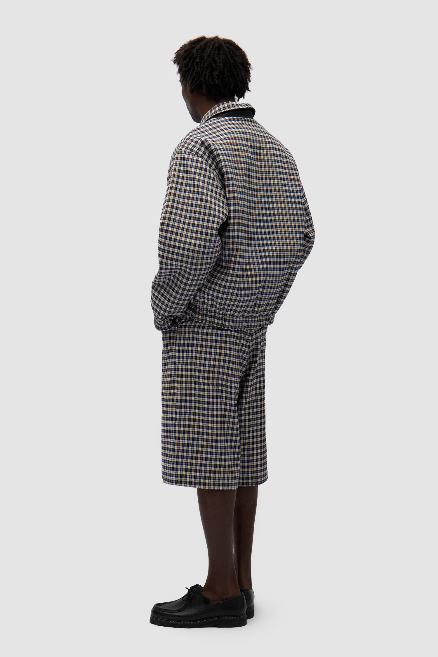 Reversible Plaid Leather Jacket in Black/Plaid worn reversed by a model, full-body back view