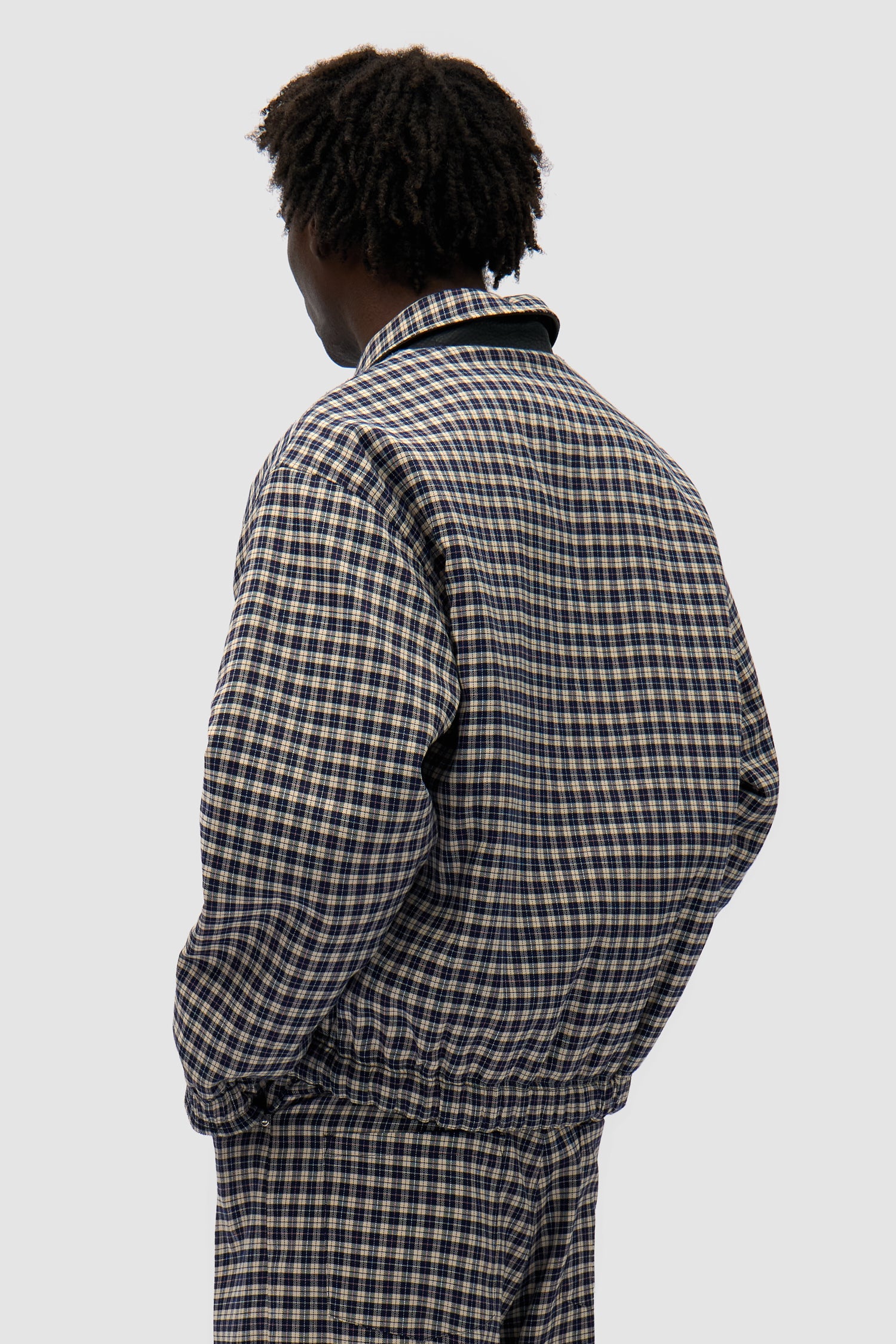 Reversible Plaid Leather Jacket in Black/Plaid worn reversed by a model, half-body side view