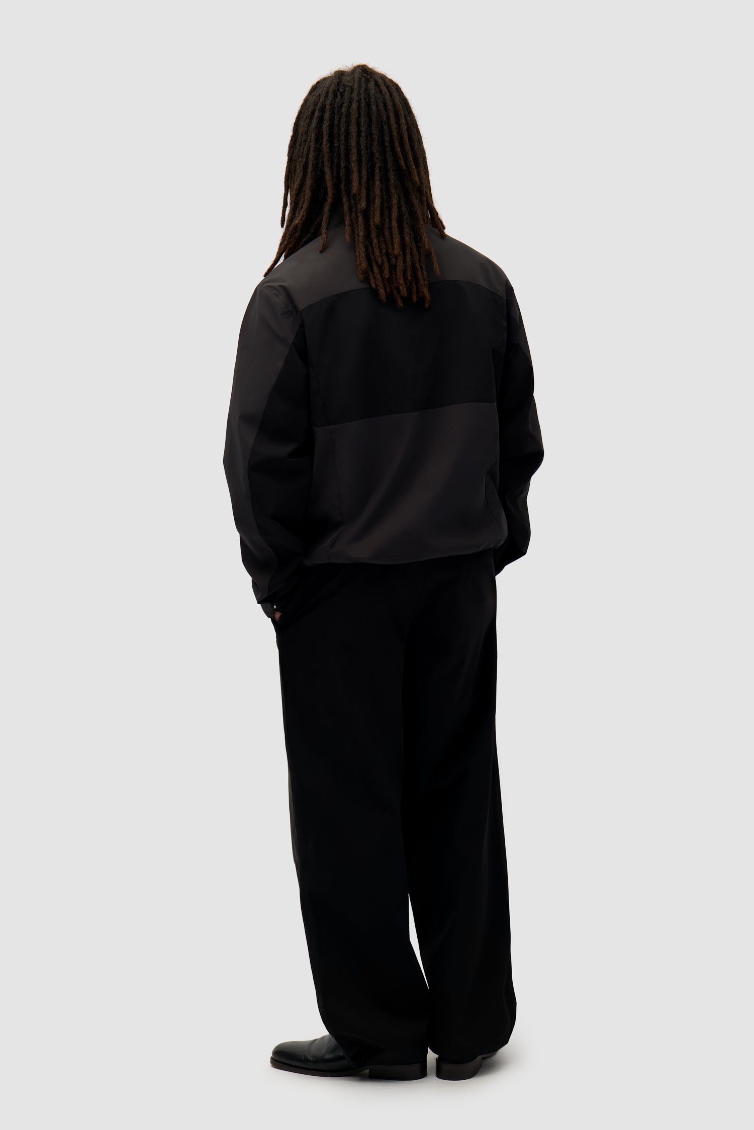 Tracksuit Jacket in Black worn by a model, full-body back view