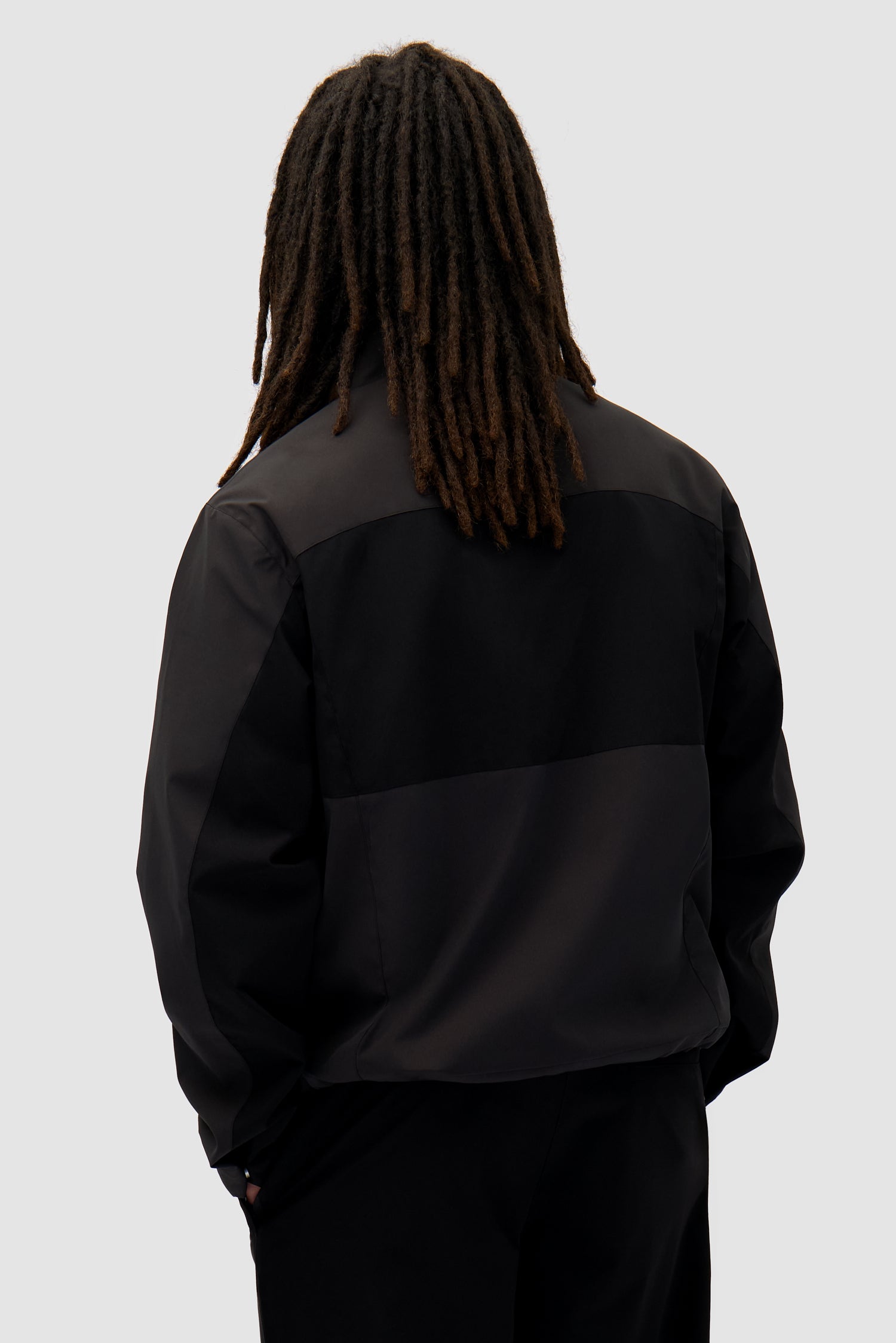 Tracksuit Jacket in Black worn by a model, half-body back view