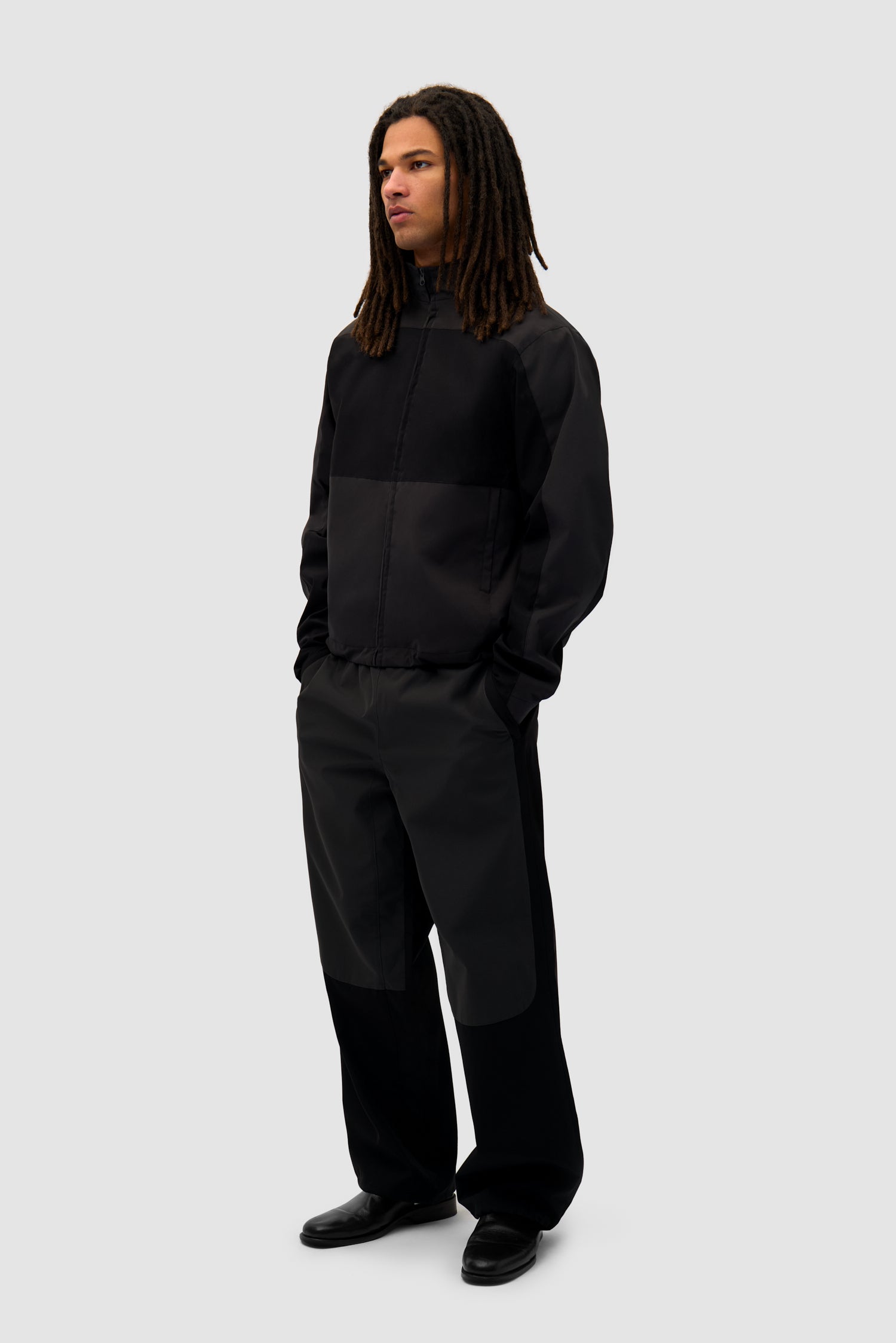 Tracksuit Jacket in Black worn by a model, full-body side view