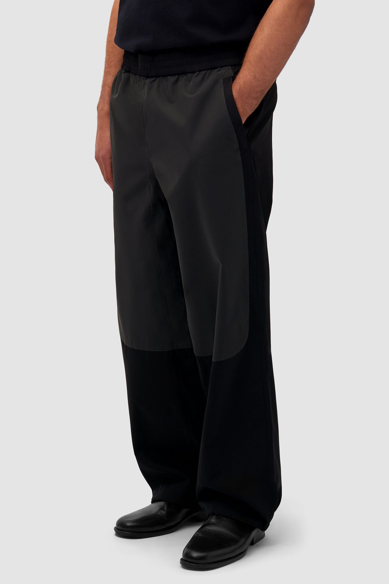 Tracksuit Pants in Black worn by a model, half-body side view