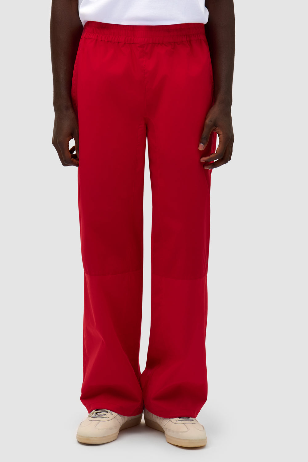 Tracksuit Pants in Red worn by a model, half-body front view