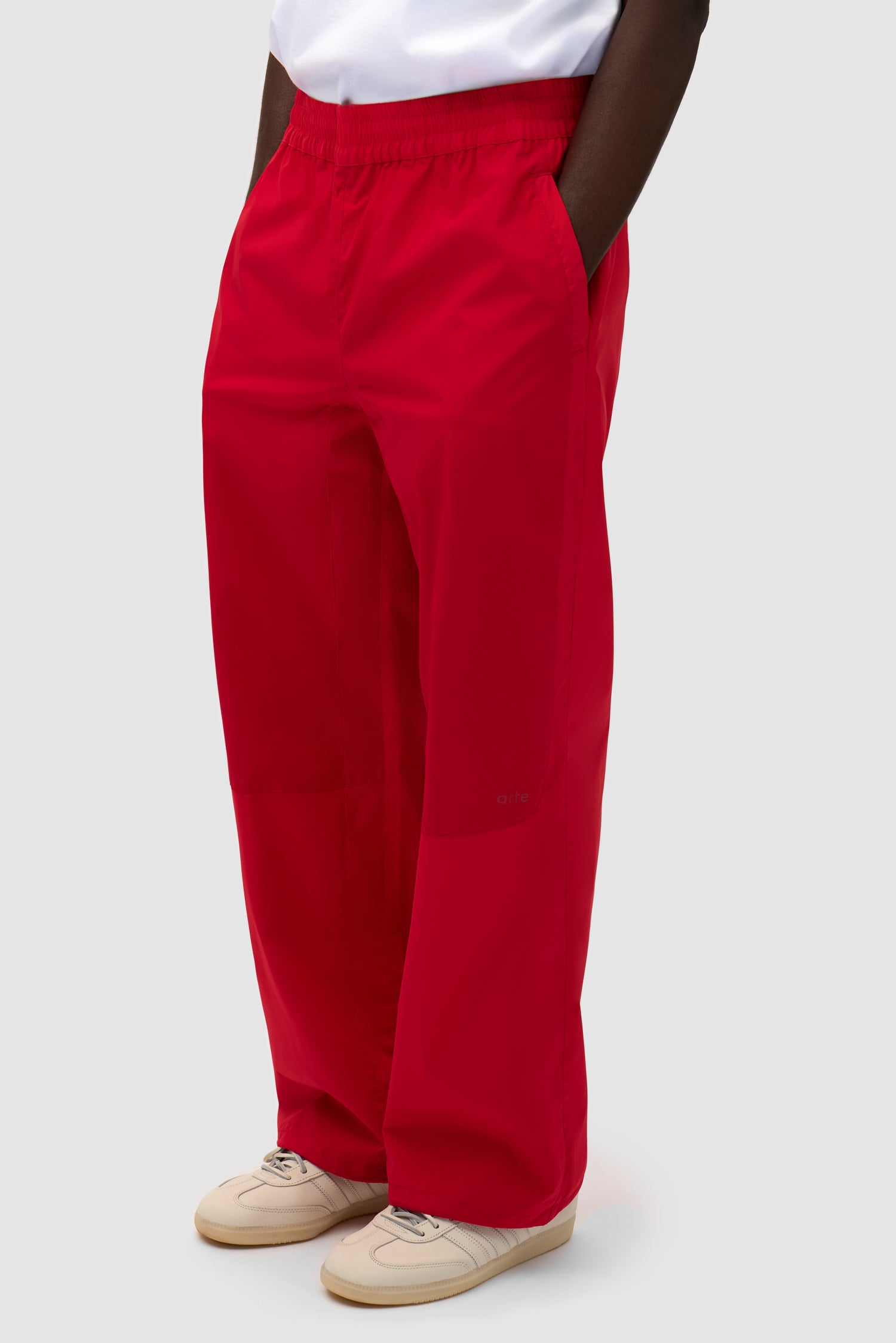 Tracksuit Pants in Red worn by a model, half-body side view