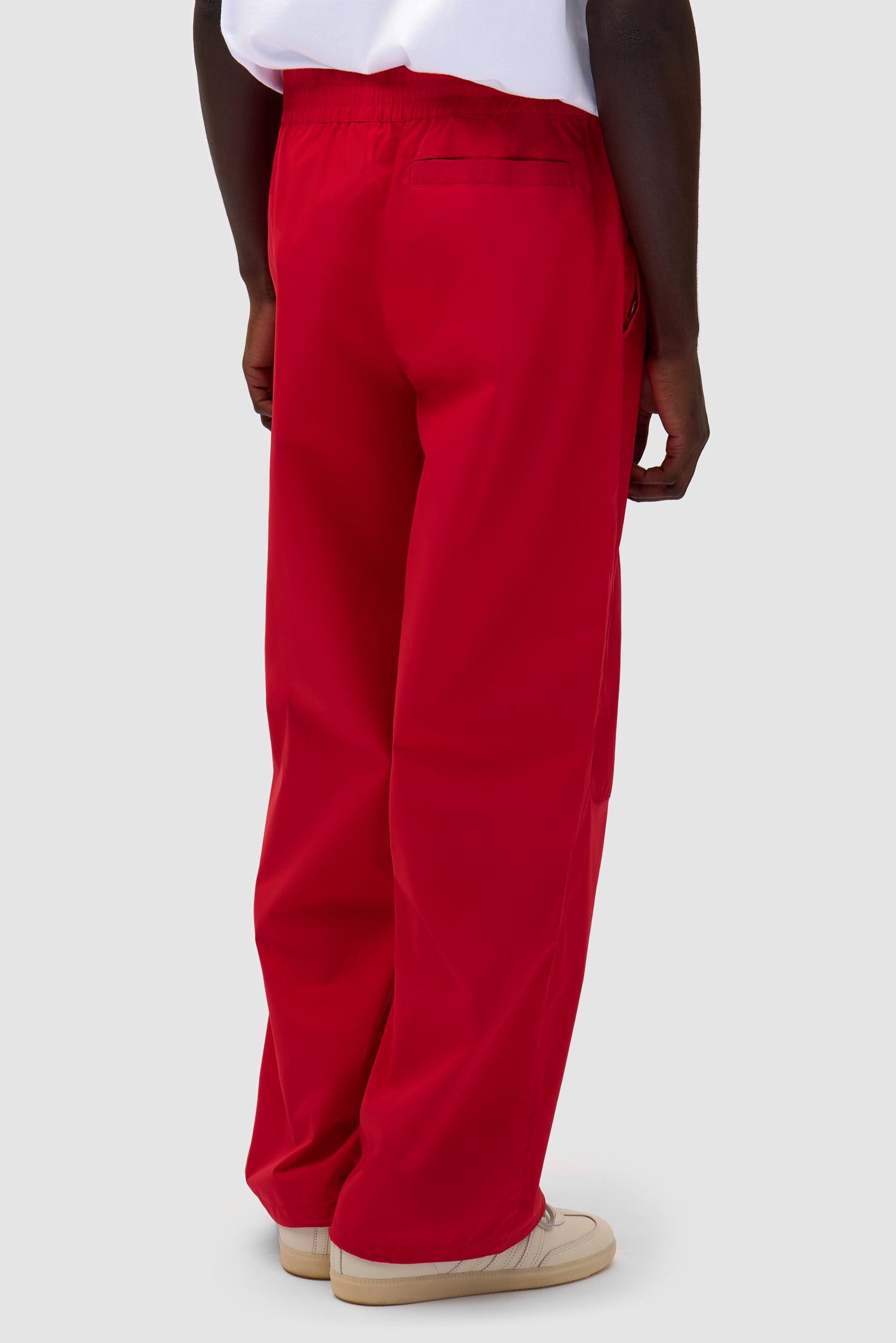 Tracksuit Pants in Red worn by a model, half-body back view