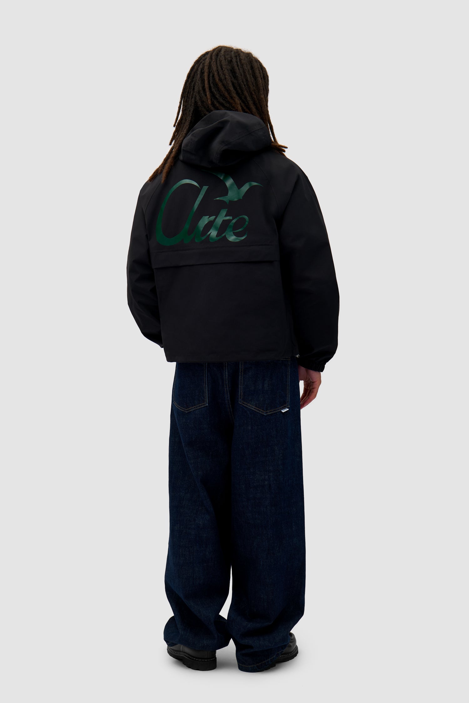 Bird Logo Anorak in Black worn by a model, full-body back view