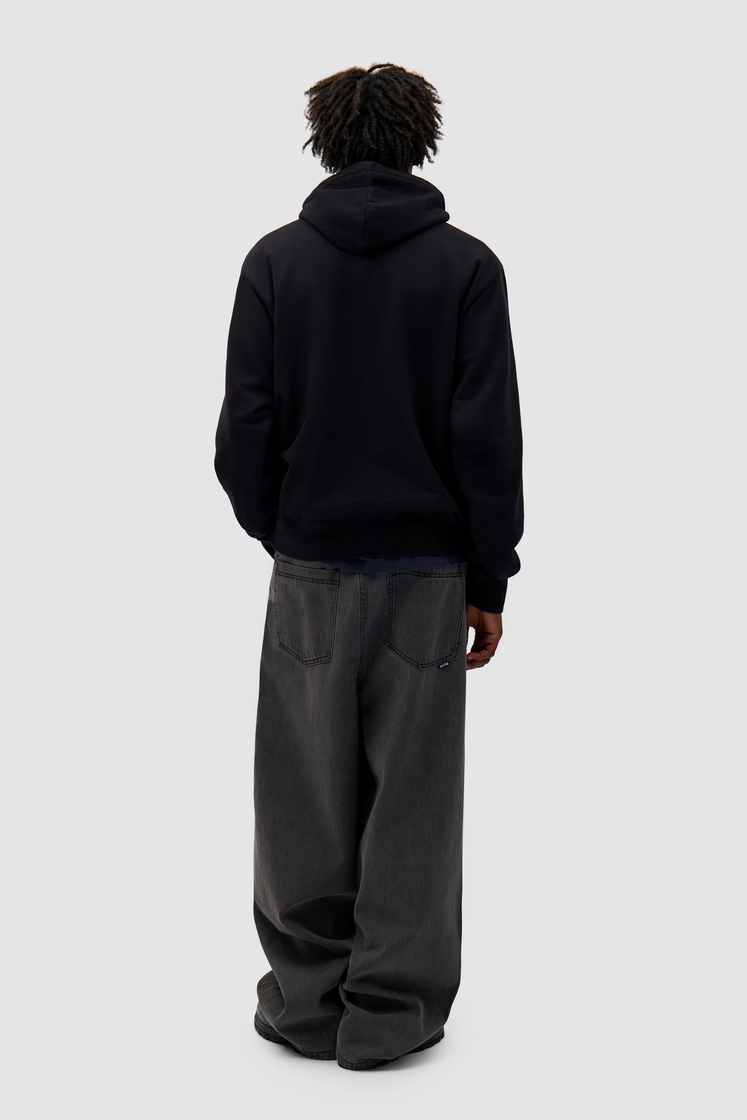 Duo Logo Hoodie in Black worn by a model, full-body side view