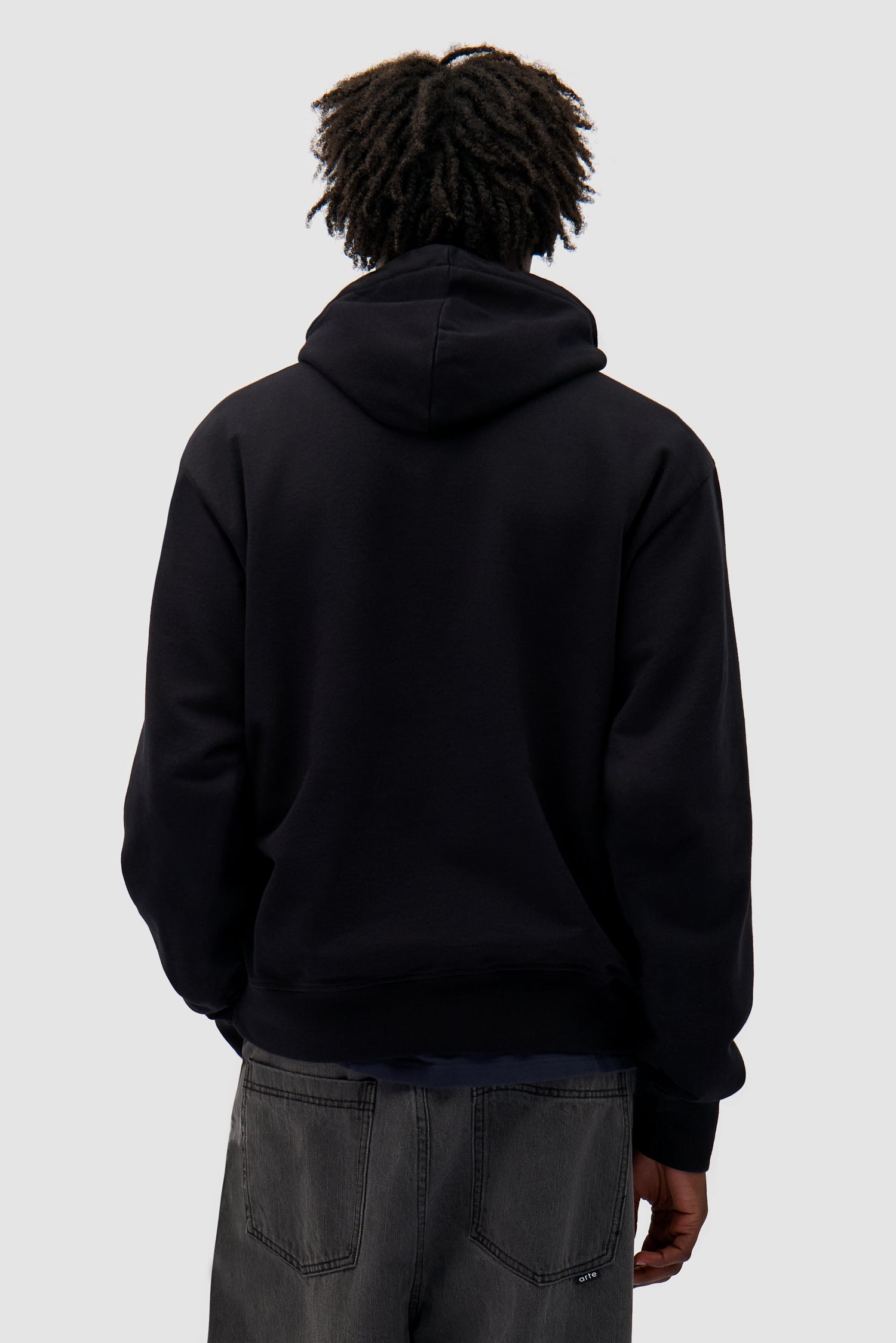 Duo Logo Hoodie in Black worn by a model, half-body back view