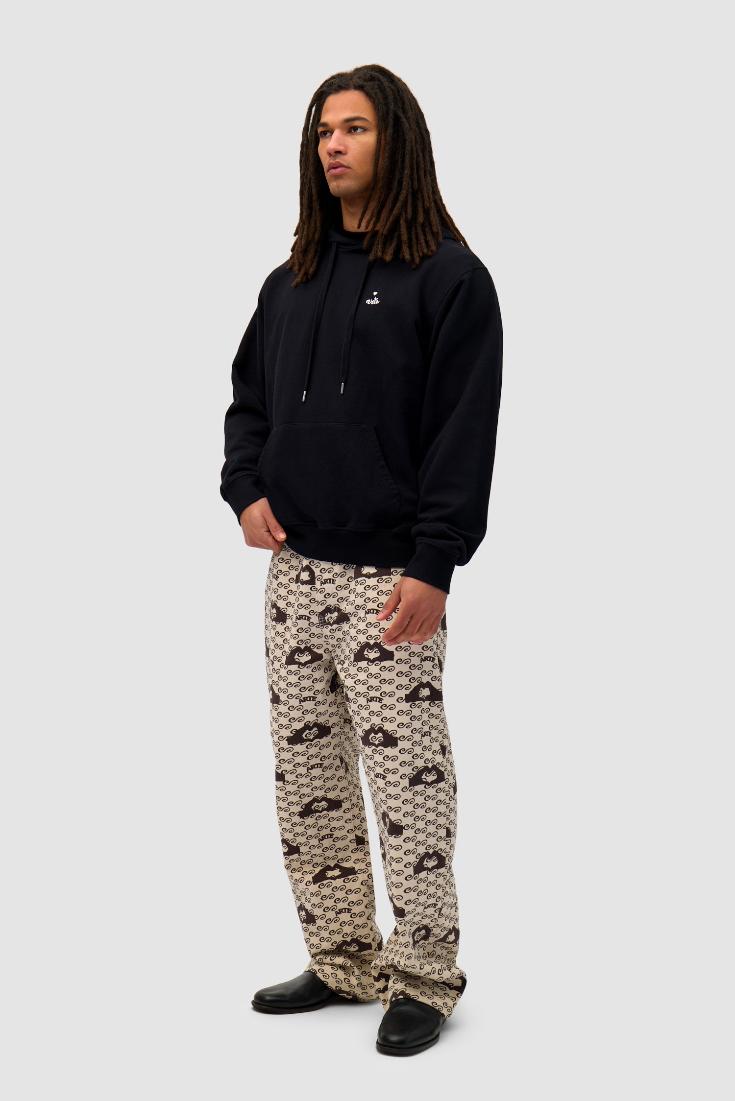 Heart Logo Hoodie in Black worn by a model, full-body side view