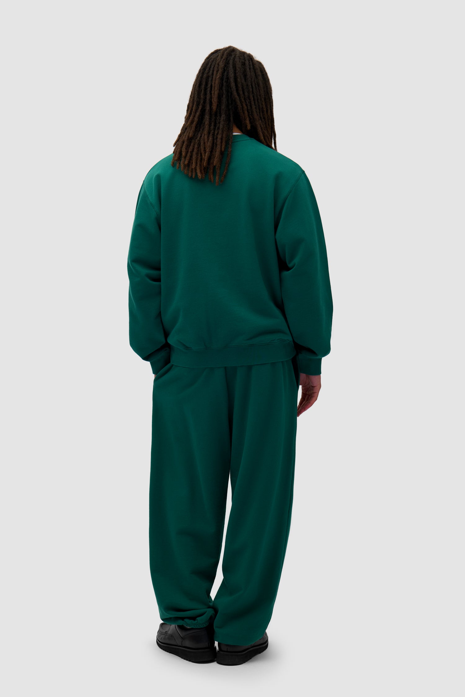 Heart Logo Sweatpants in Green worn by a model, full-body back view