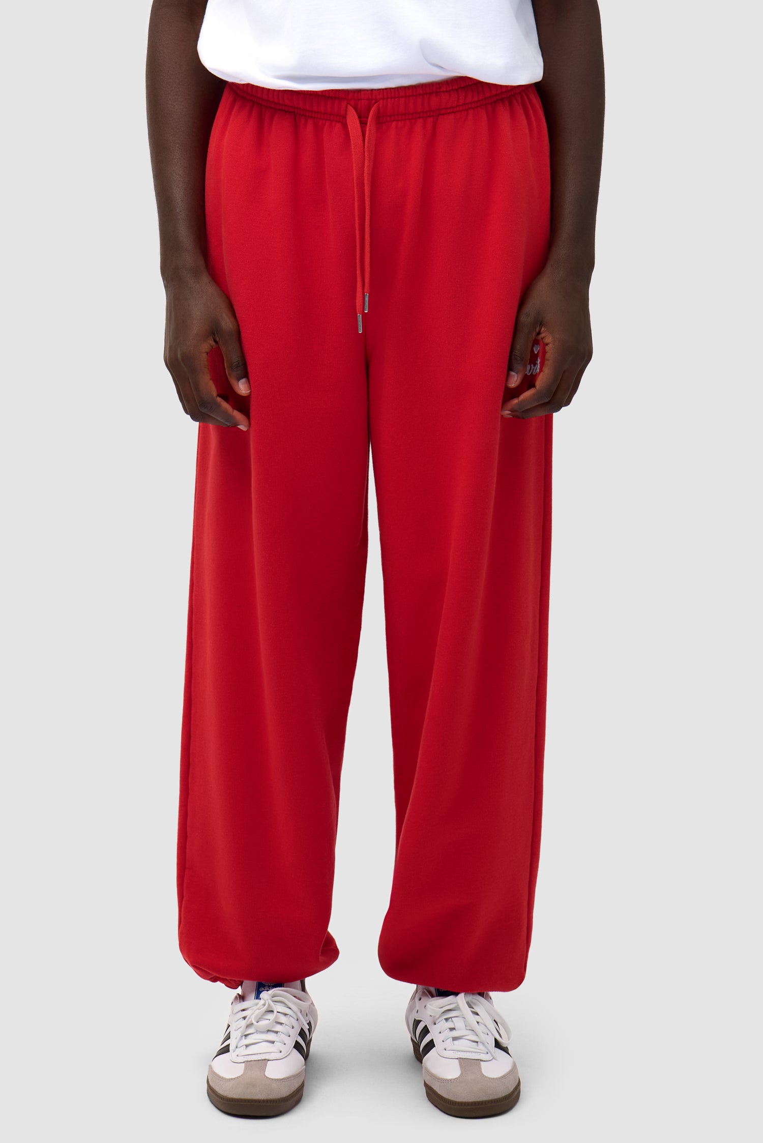 Heart Logo Sweatpants in Red worn by a model, half-body side view