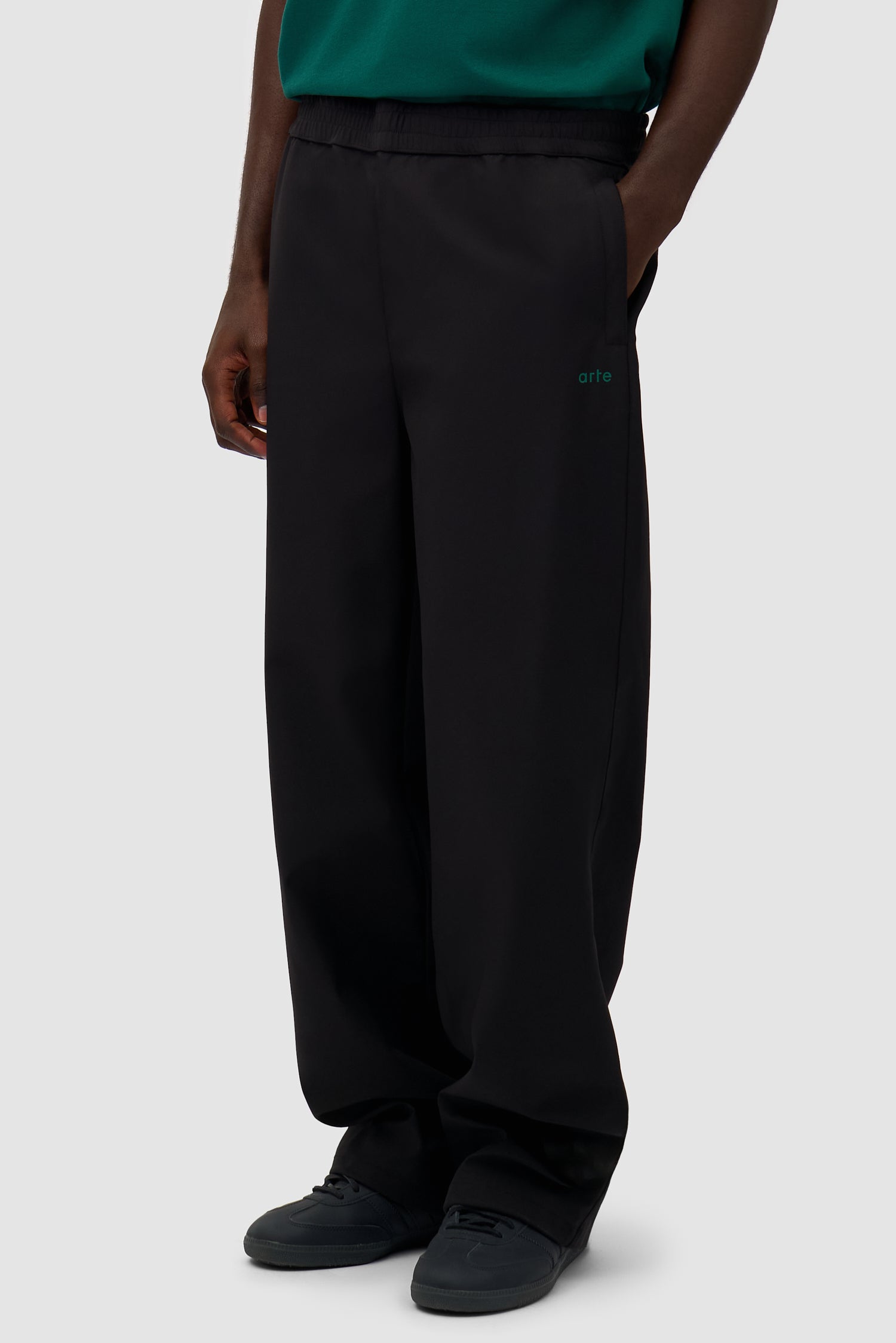 Green Logo Polyester Pants in Black worn by a model, half-body side view