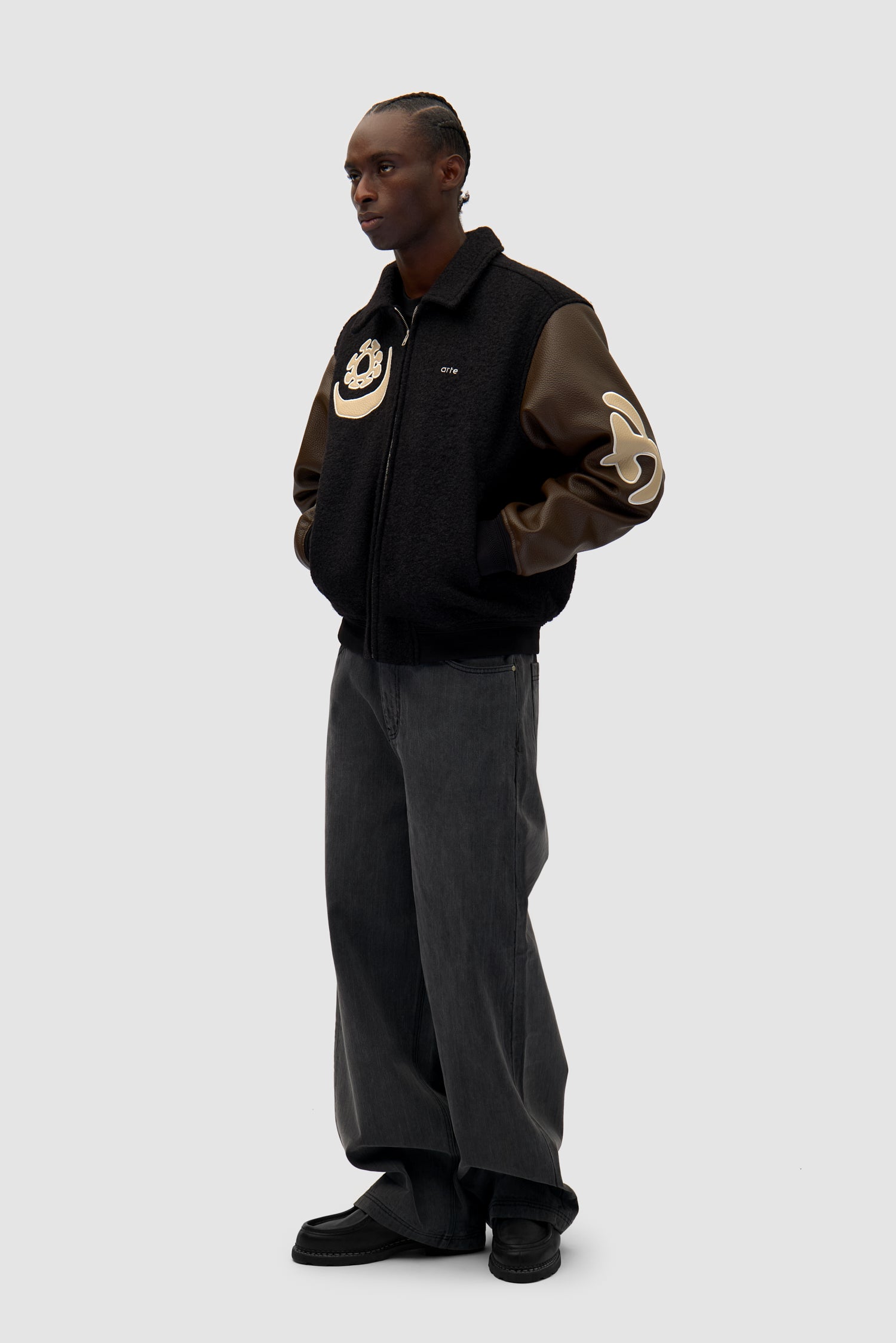 Varsity Jacket in Black/Brown worn by a model, full-body side view