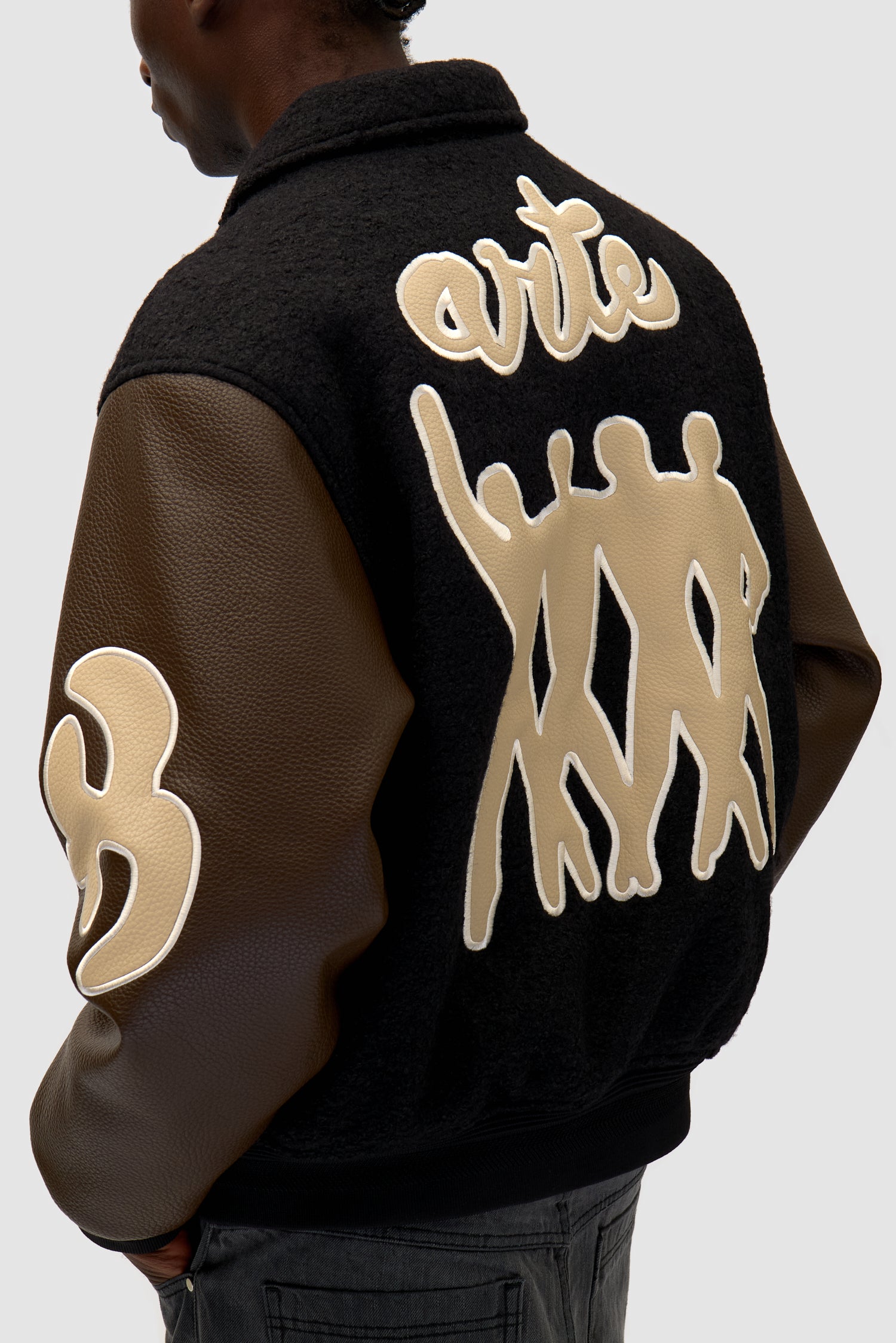 Varsity Jacket in Black/Brown worn by a model, half-body detailed view