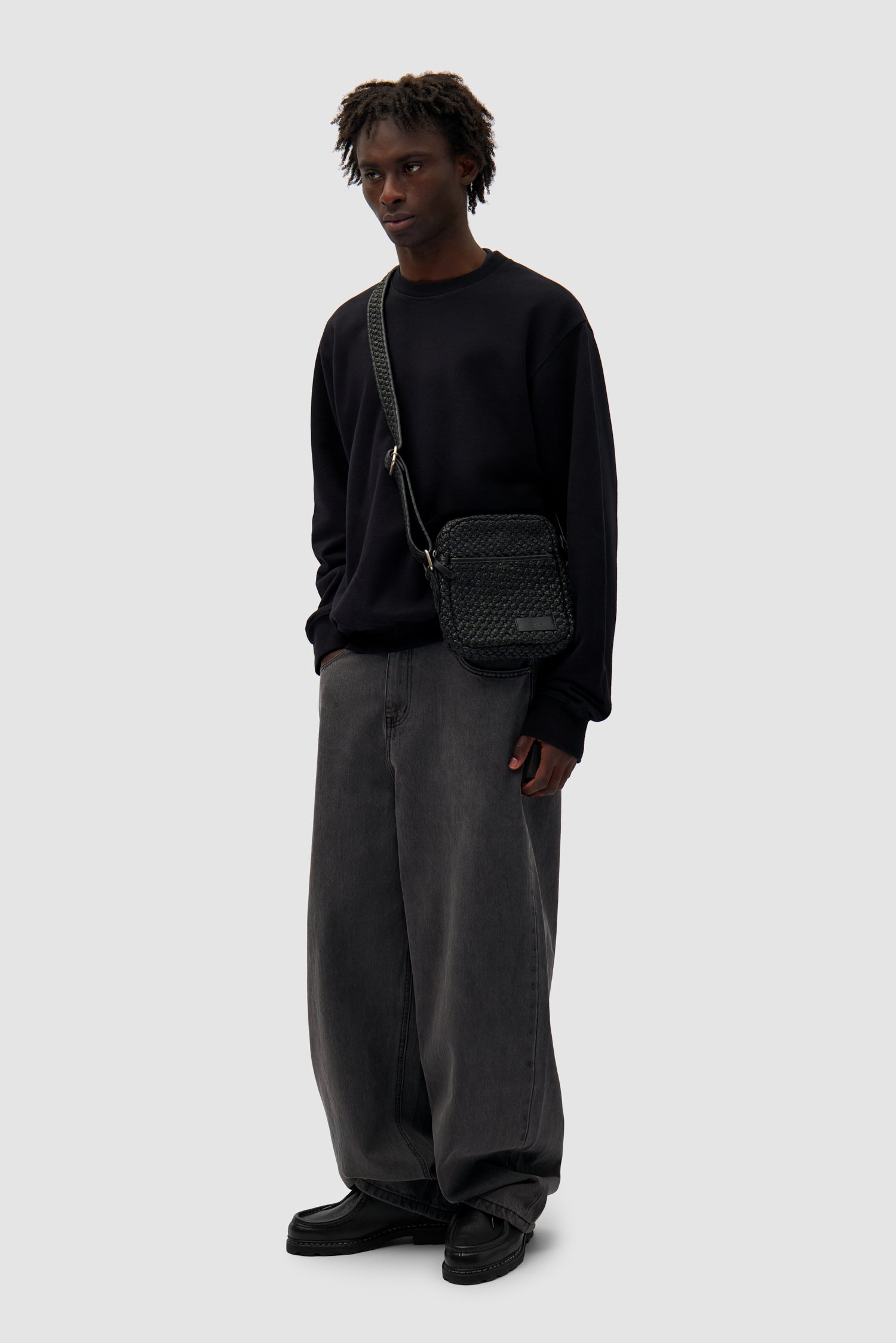 Small Braided Leather Bag in Black worn by a model, full-body front view