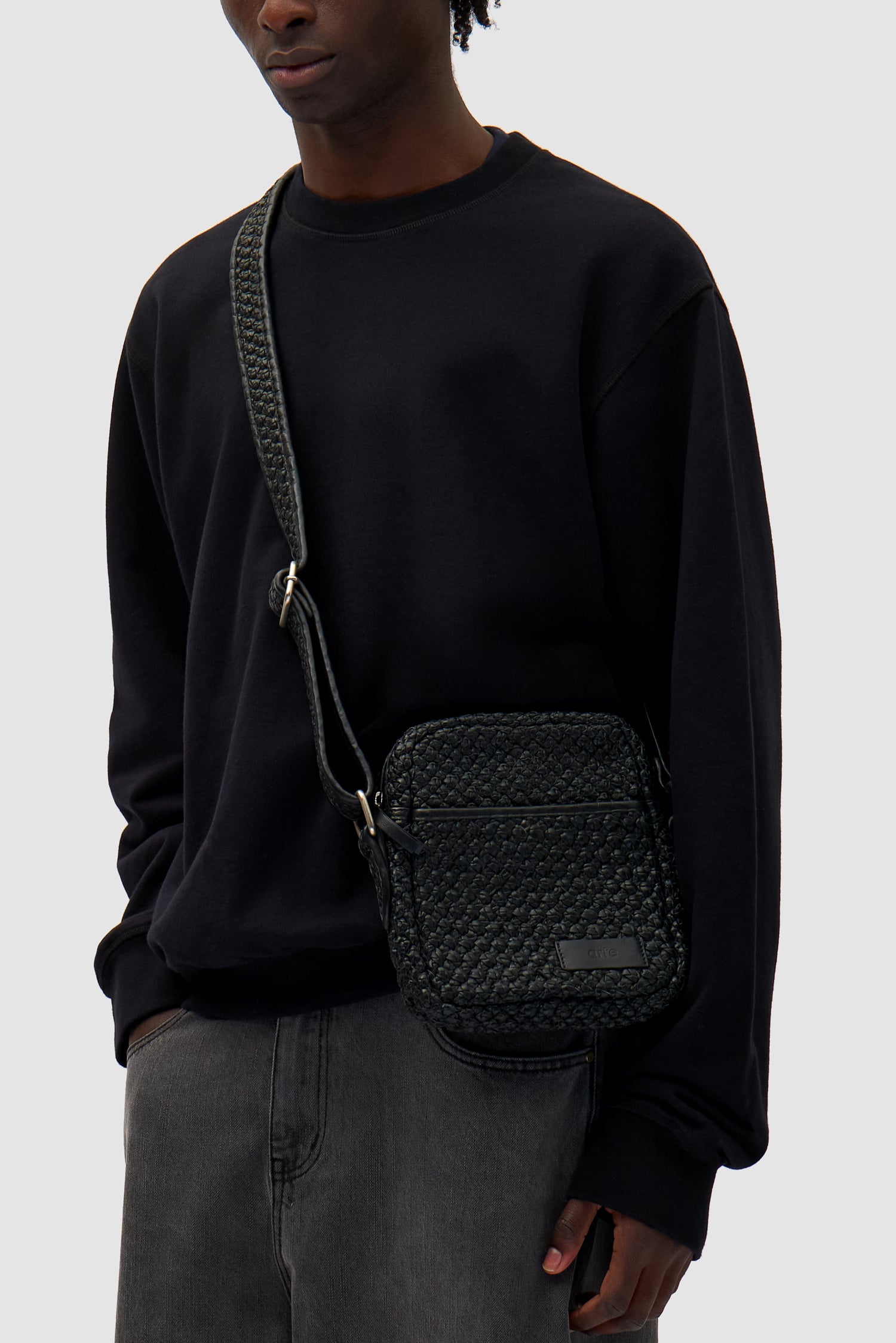 Small Braided Leather Bag in Black worn by a model, half-body front view