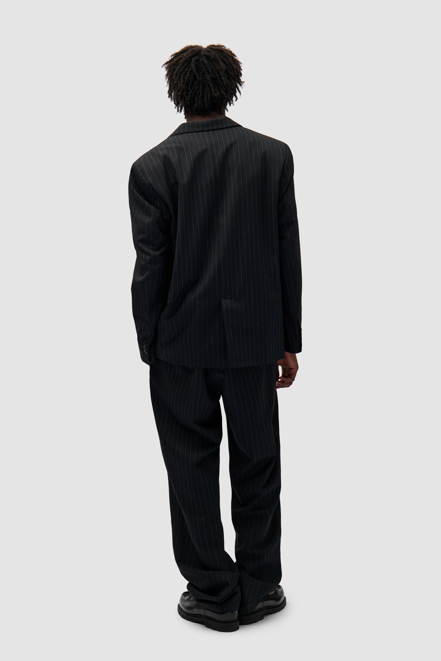Suit Jacket in Black worn by a model, full-body back view