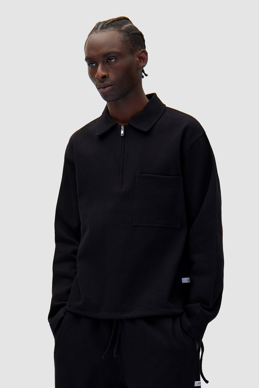 Label Pullover in Black worn by a model, half-body front view