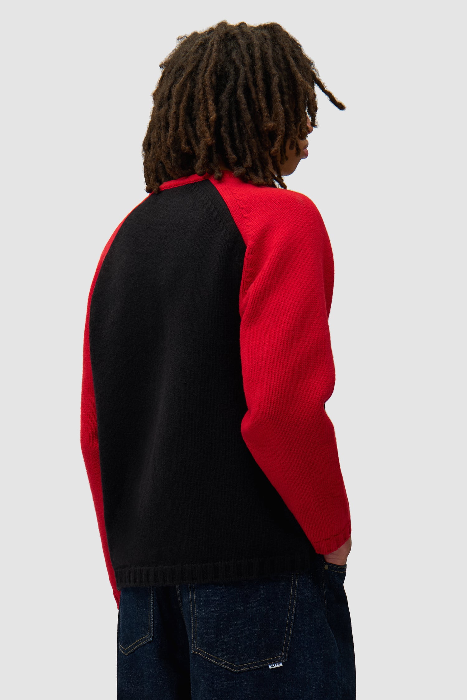 Knitted Longsleeve in Black/Red worn by a model, half-body back view